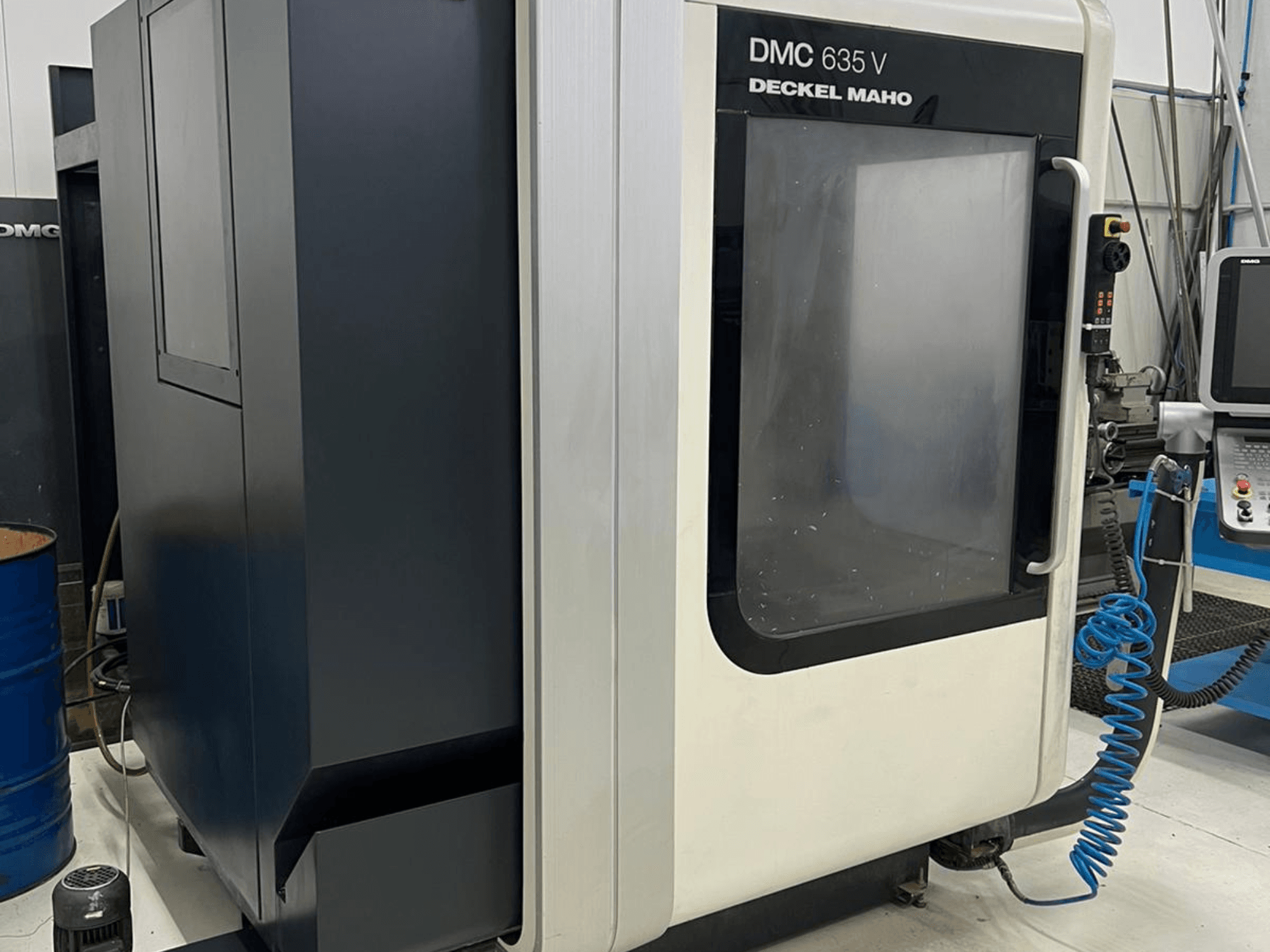 Deckel Maho DMC 635 V frēzmašīna, sānu skats, kurā redzams vadības panelis un daļēji atvērtas piekļuves durvis.