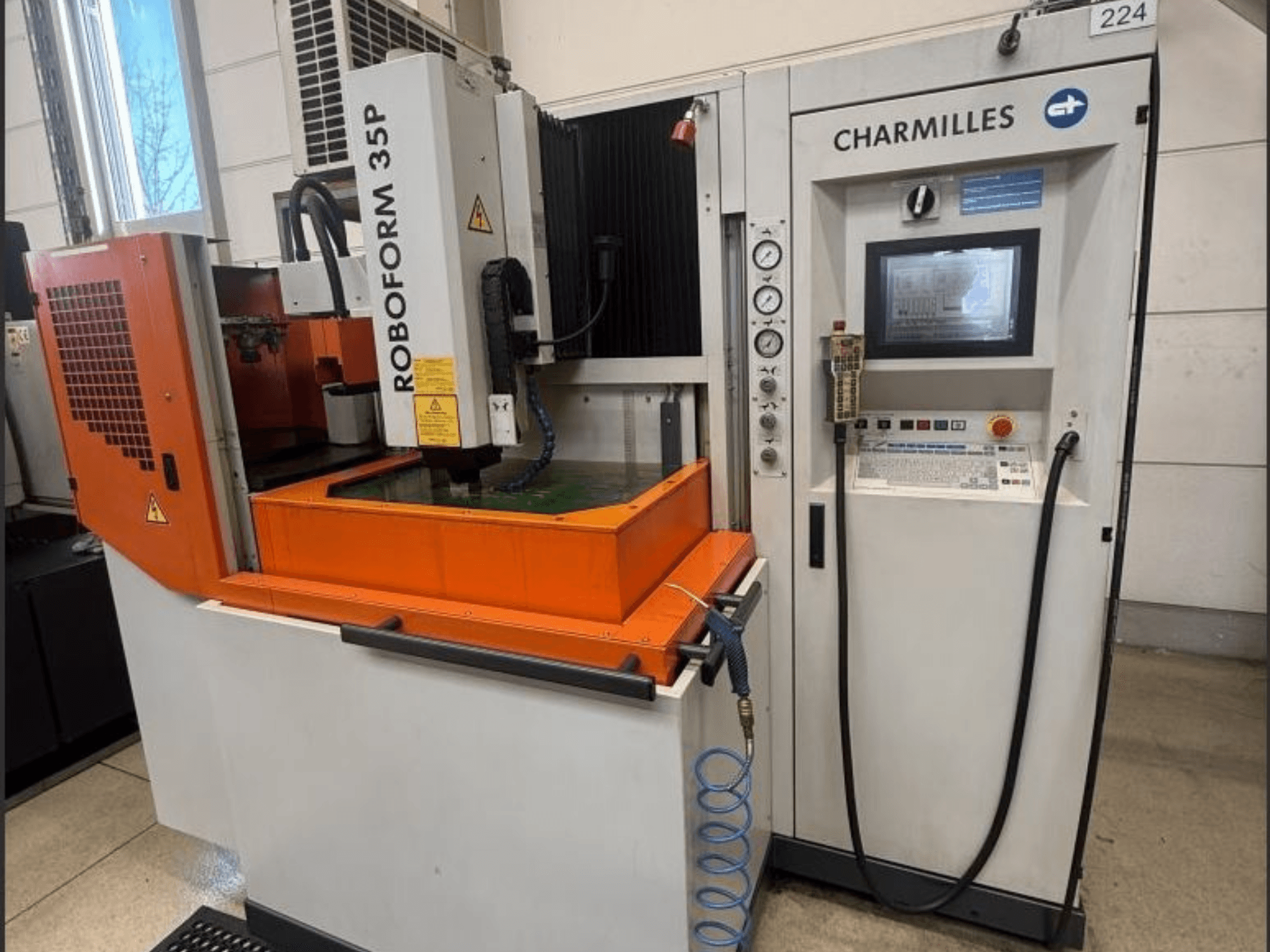 Charmilles ROBOFORM 35P štancēšanas EDM mašīna, priekšējais skats, ar vadības paneli, portālu un šķidruma tvertni darbībā.