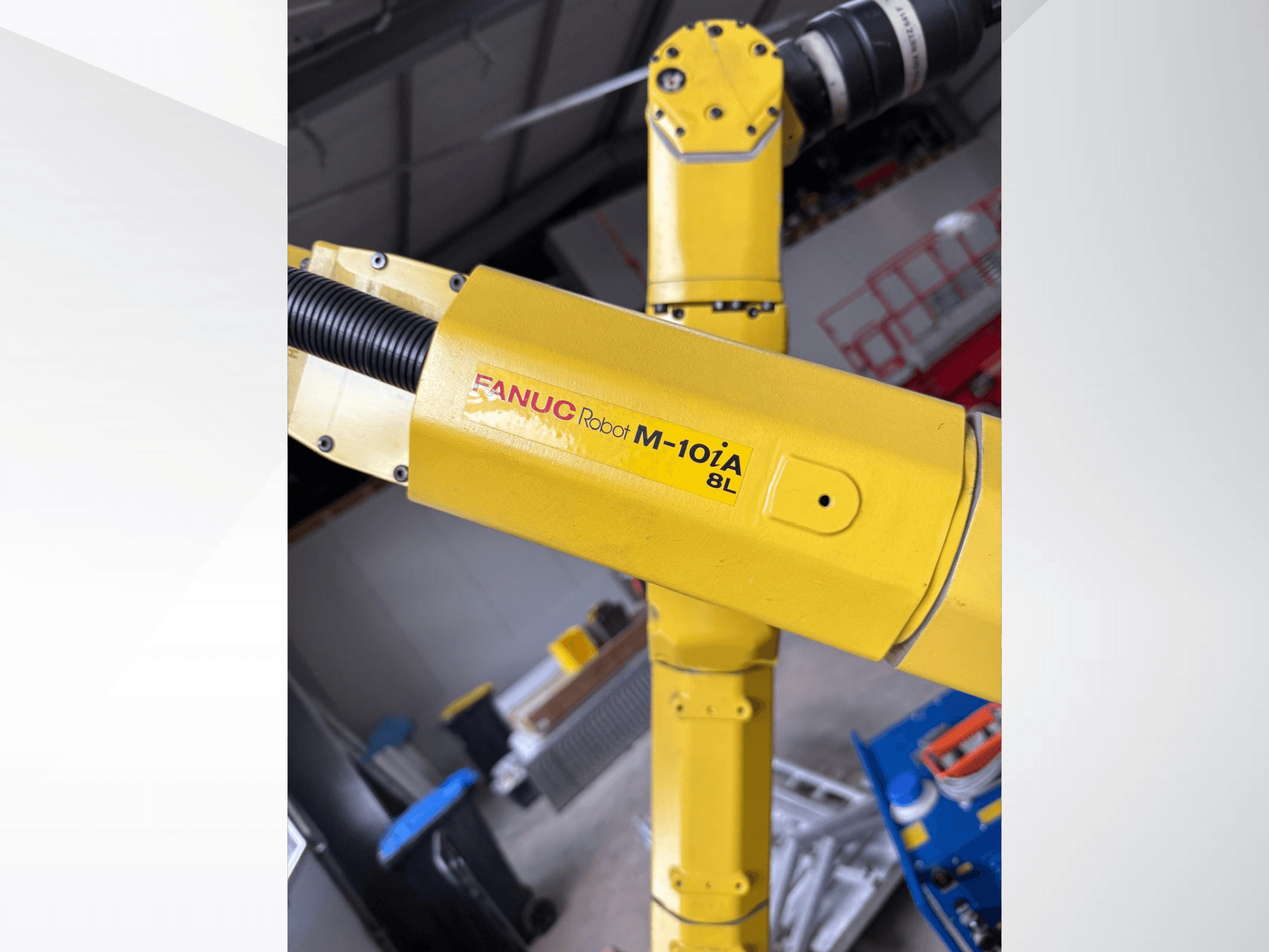 FANUC robots M-10iA 8L dzeltenā krāsā, skatoties no sāniem, demonstrē rokas locītavu un mehāniskos komponentus rūpnieciskā vidē.