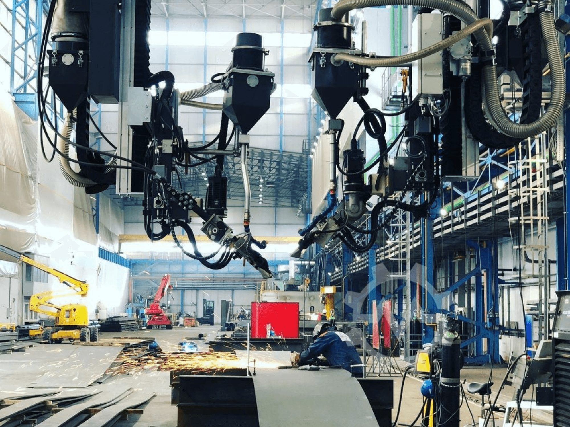 Robotizēta griešanas iekārta rūpnieciskā vidē, no sāniem redzamas lidojošas dzirksteles; ar vairākiem stiprinājumiem un šļūtenēm.