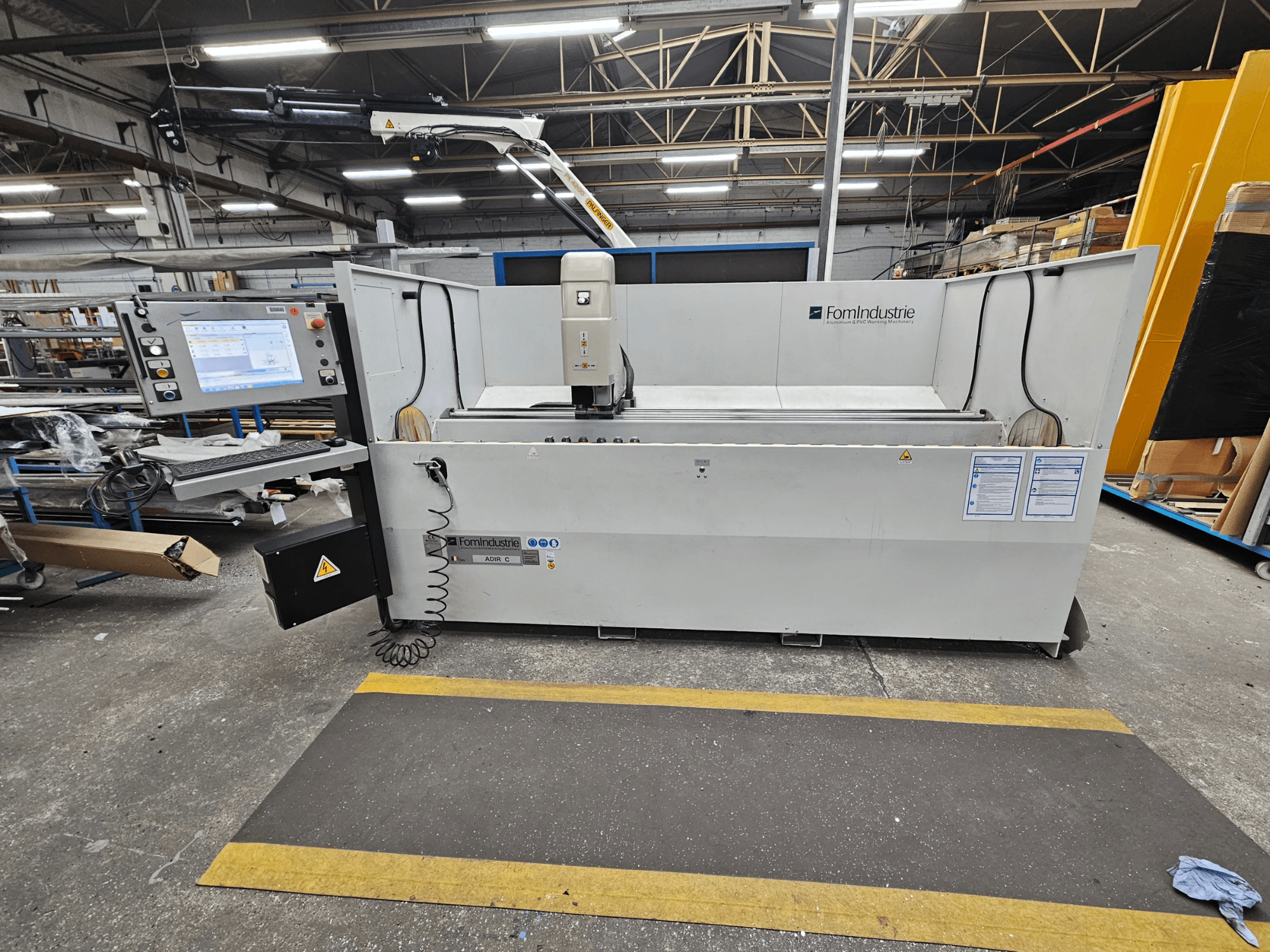 FomIndustrie ADIR C vertikālais apstrādes centrs darbnīcā, priekšējais skats, kurā redzams vadības panelis un mašīnas detaļas.