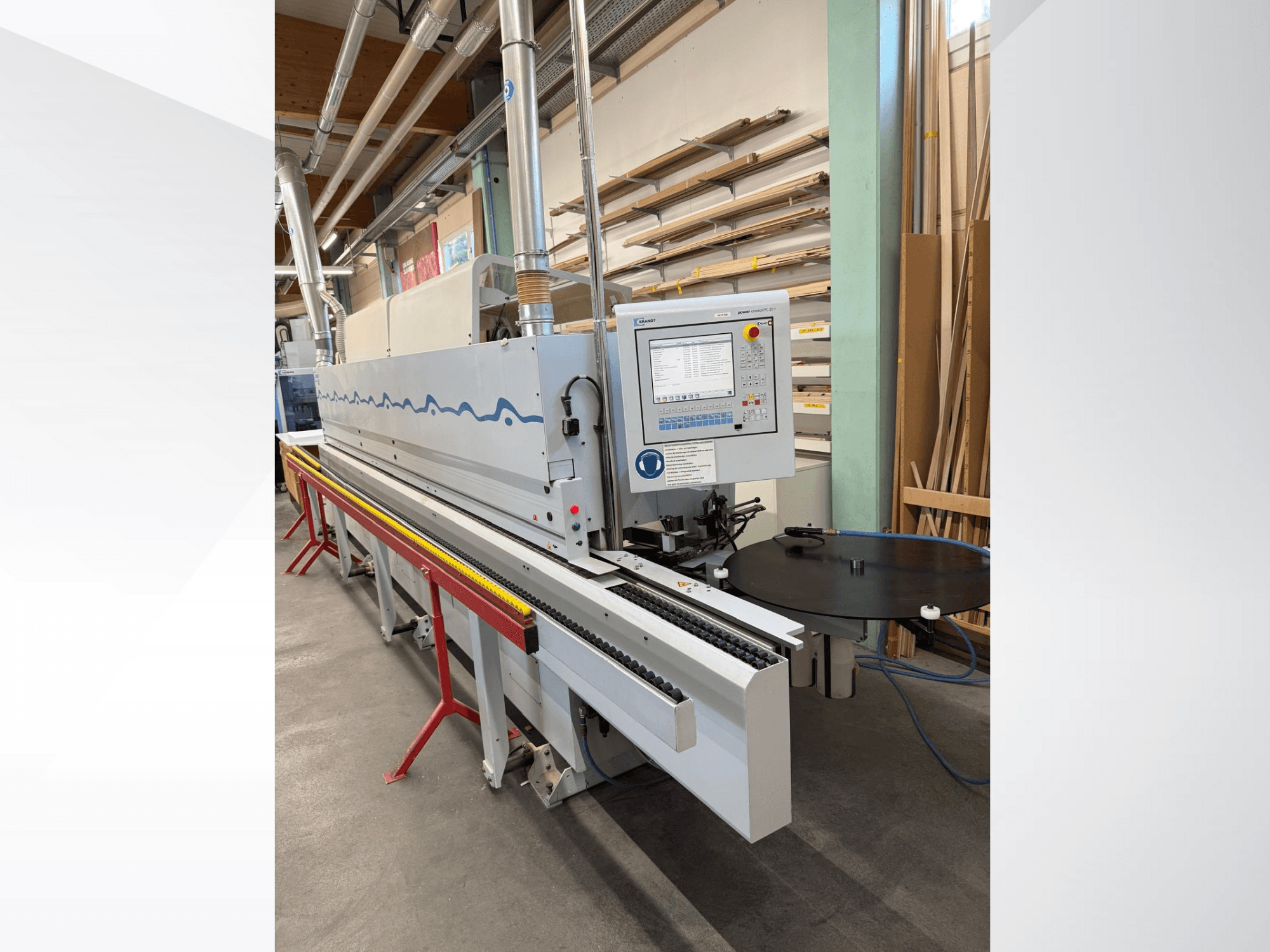 Priekšējais skats uz HolzHer automātisko malu līmēšanas iekārtu ar vadības paneli, transportēšanas sistēmu un apaļo atbalsta galdu.