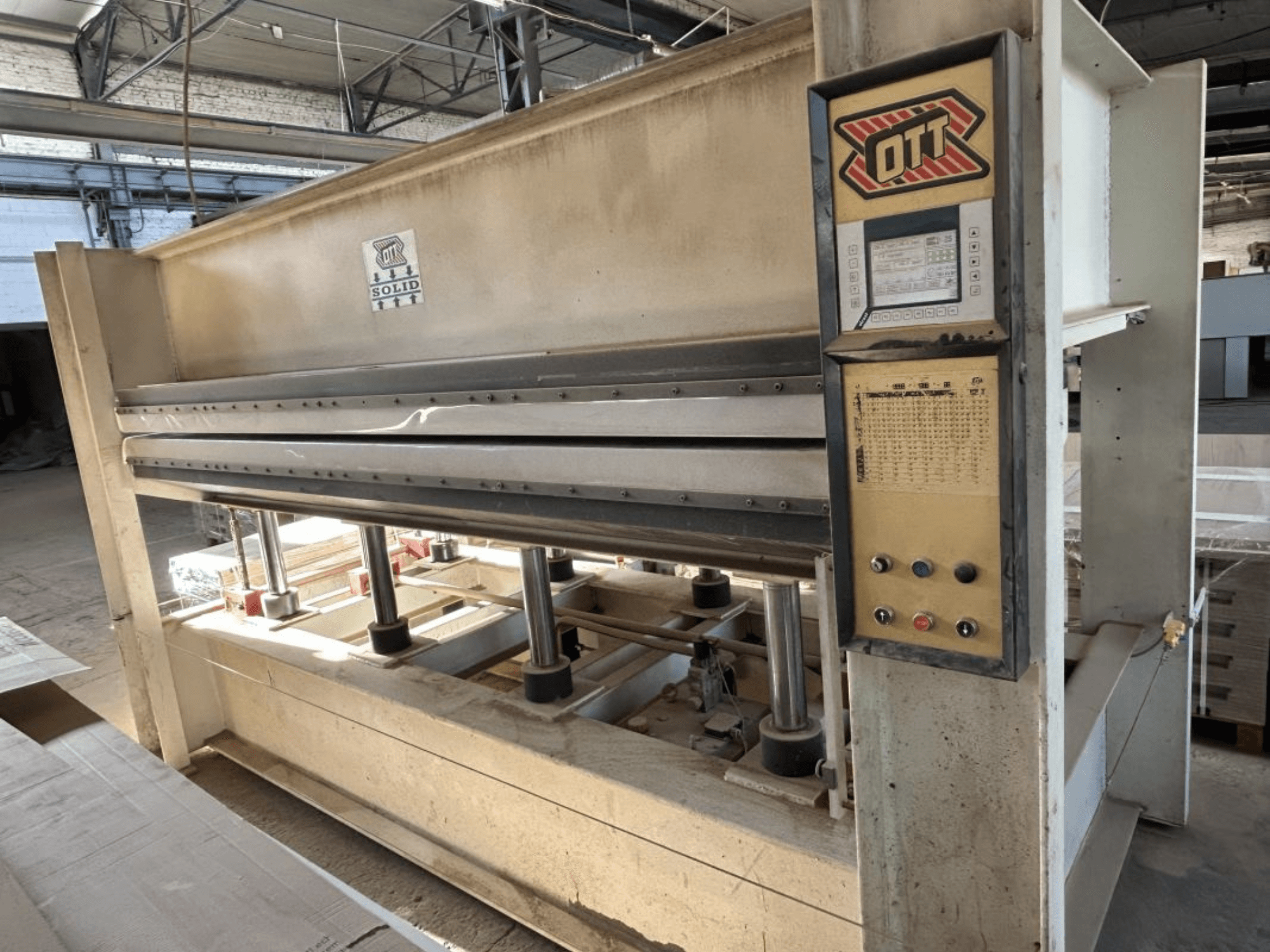OTT SOLID 16-32 laminēšanas preses skats no priekšpuses, kurā redzams vadības panelis un hidrauliskās detaļas.