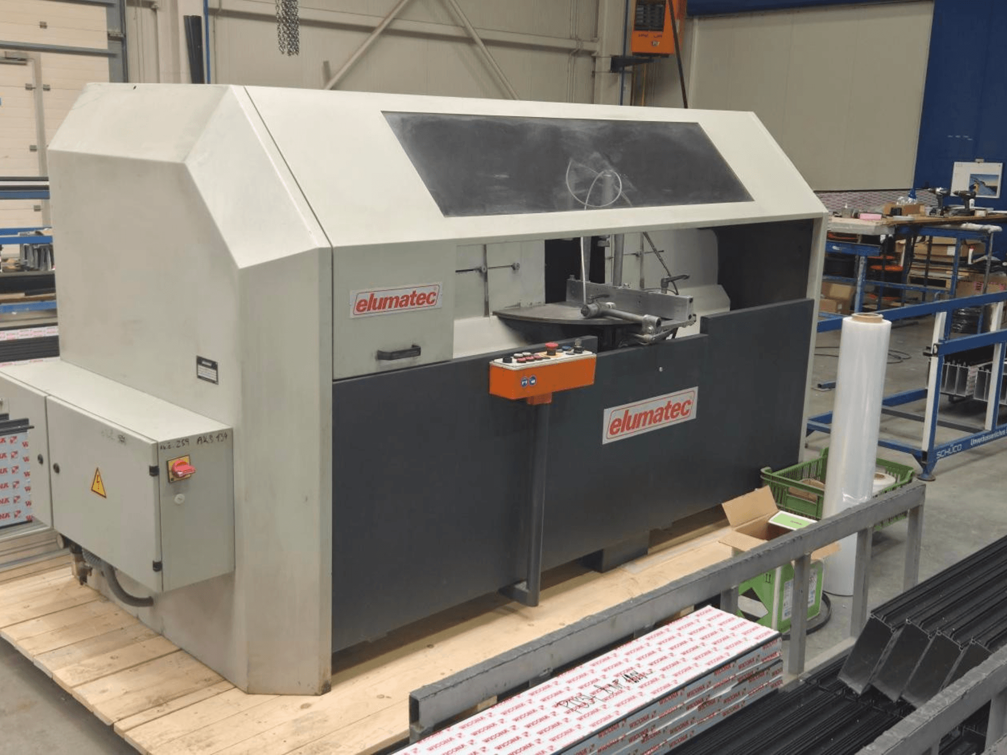 Elumatec AKS 134 ripzāģis metālam, skats no priekšpuses, redzams vadības panelis un griešanas zona uz koka platformas.