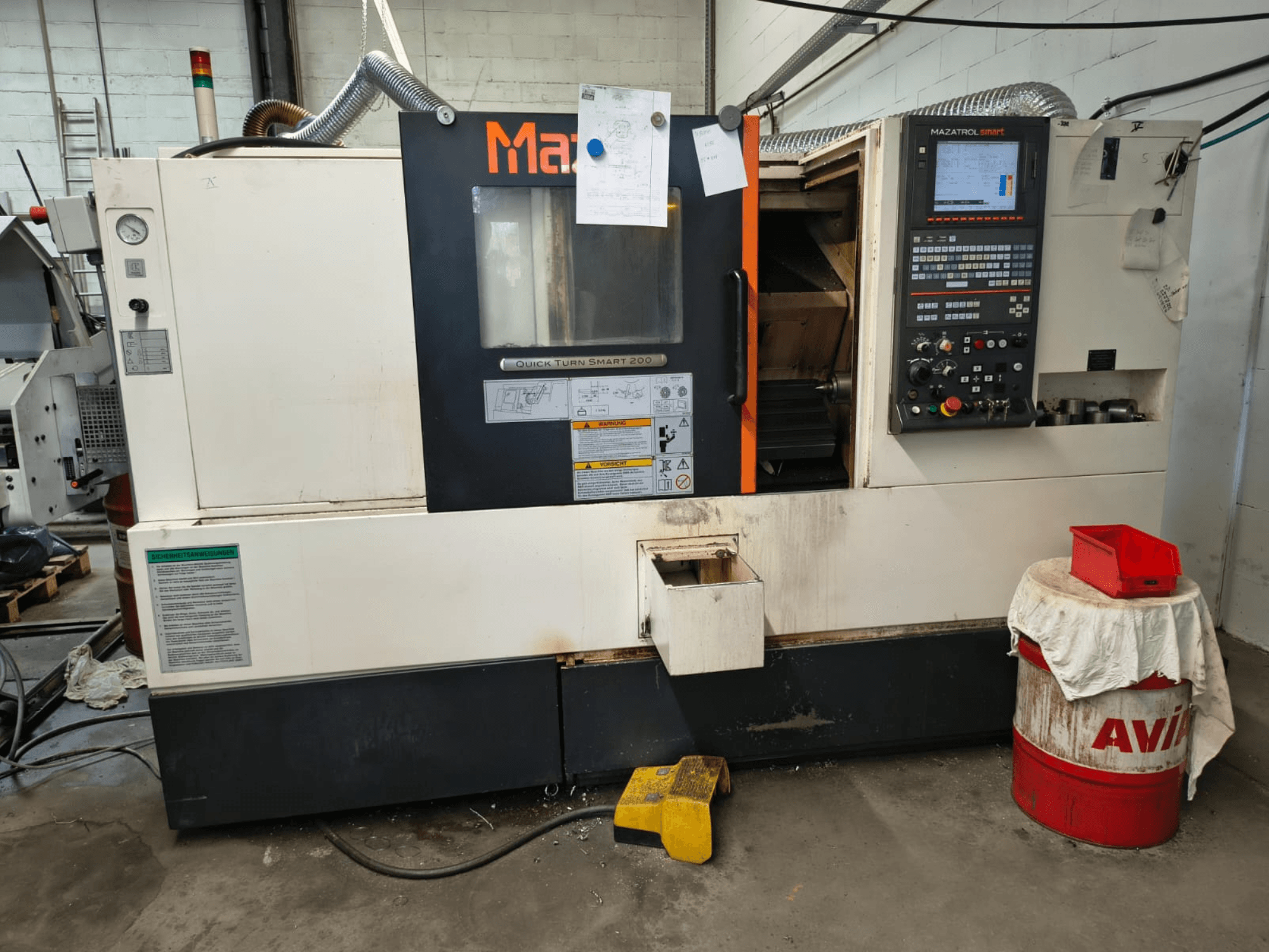 Mazak Quick Turn Smart 200, horizontāla virpošanas mašīna, skats no priekšpuses, kurā redzams vadības panelis, dzesēšanas šķidruma tvertne un marķējumi.