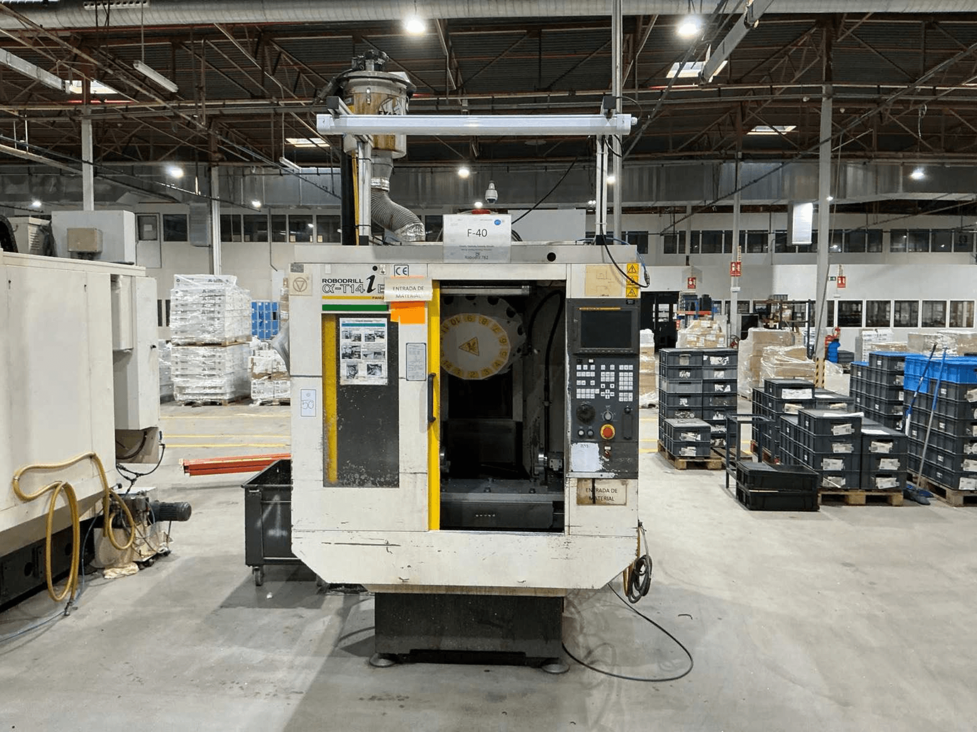 FANUC ROBODRILL α-T14iB vertikālais apstrādes centrs rūpnīcā, priekšējais skats, kurā redzams vadības panelis un instrumentu turētājs.