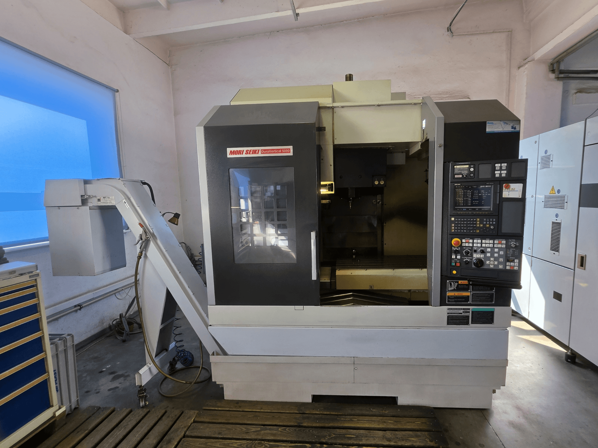 Vertikālais apstrādes centrs MORI SEIKI DuraVertical 5080, skats no priekšpuses, kurā redzams vadības panelis, vārpsta un instrumentu turētājs.