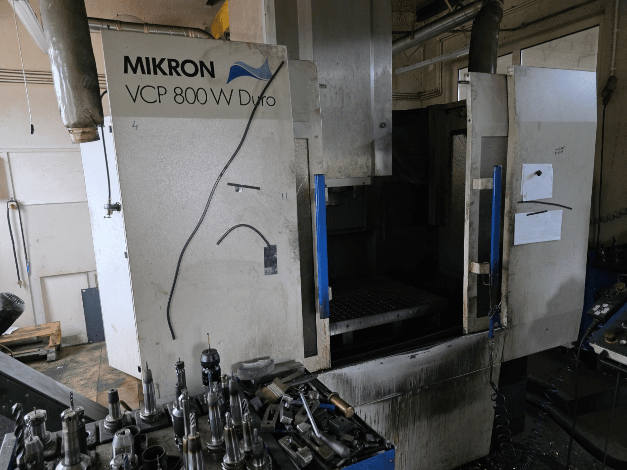 Mikron VCP 800 W Duro frēzmašīna no sānu skata, priekšplānā redzami darbarīki un vadības ierīces.