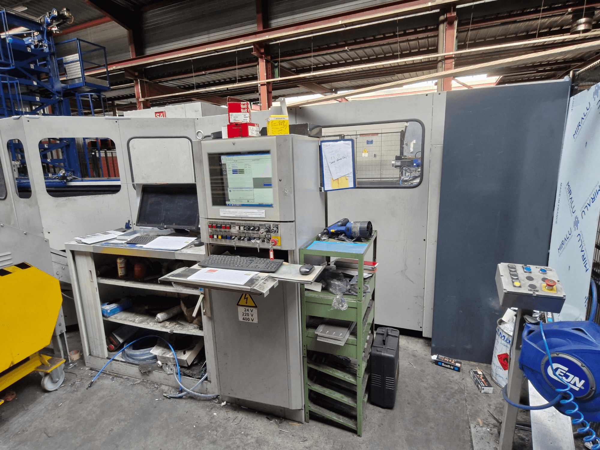 CNC caurumošanas iekārta Salvagnini S4-40 darbnīcā, ar vadības paneli ar monitoriem un instrumentiem, skats no priekšpuses.