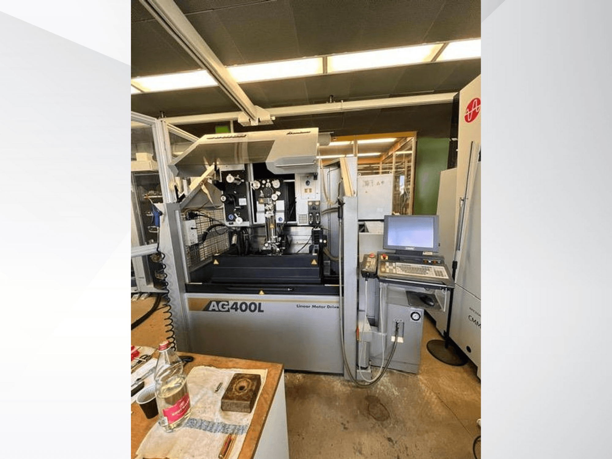 AG400L lineārā motordzinēja piedziņas mašīna, skats no priekšpuses, ar vadības paneli un darba zonu ar redzamiem drošības elementiem.