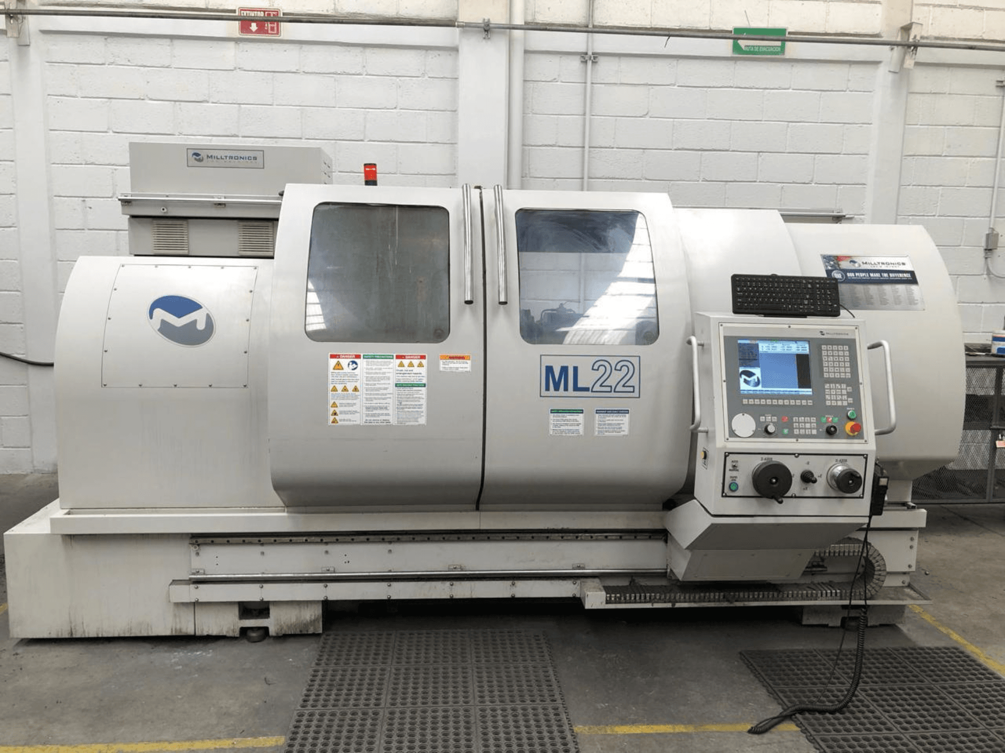 Vertikālais apstrādes centrs MILLTRONICS RH 20, priekšējais skats, kurā redzams vadības panelis, zīmola logotips un drošības marķējums uz mašīnas.