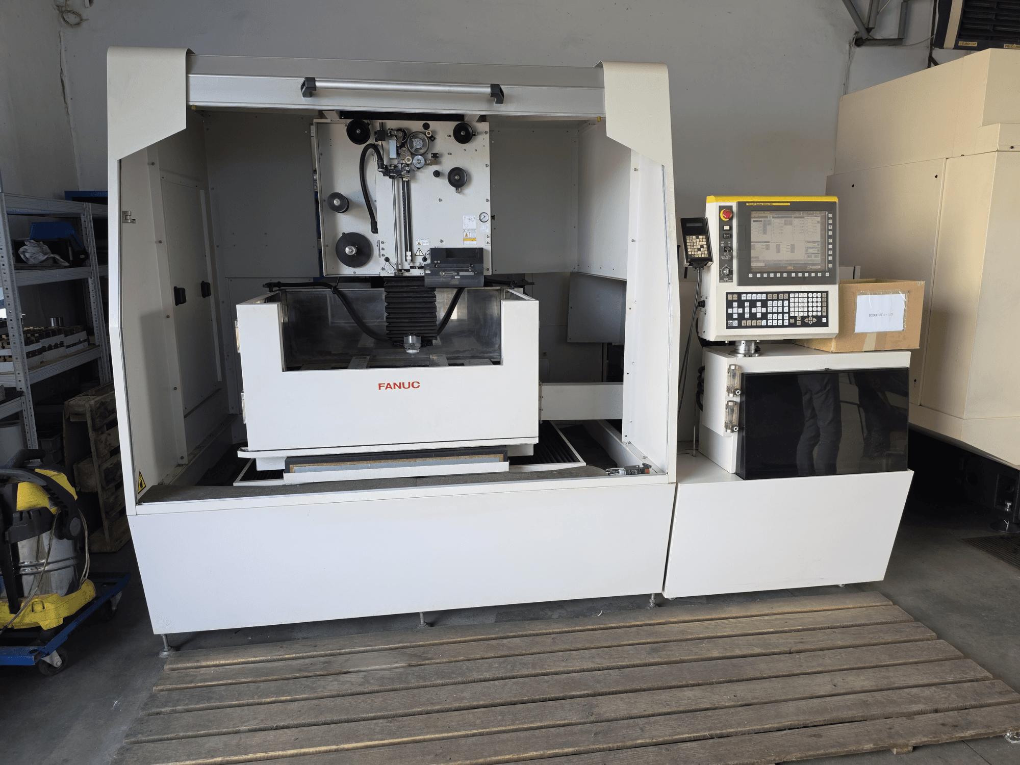 FANUC ROBOCUT alpha-1iD stiepļu elektroerozijas mašīna — skats no priekšpuses, kurā redzams vadības panelis, darba zona un kompaktais dizains darbnīcas vidē.
