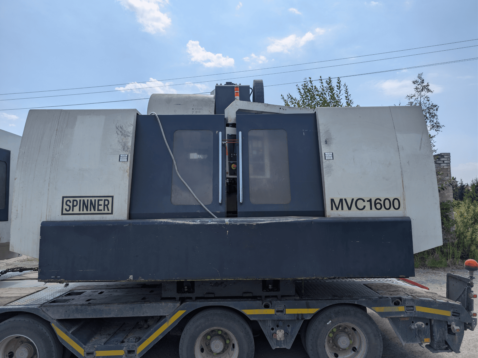 Vertikālais apstrādes centrs SPINNER MVC 1600, skats no priekšpuses uz kravas automašīnas, kurā redzams zīmols un plaša apstrādes zona.