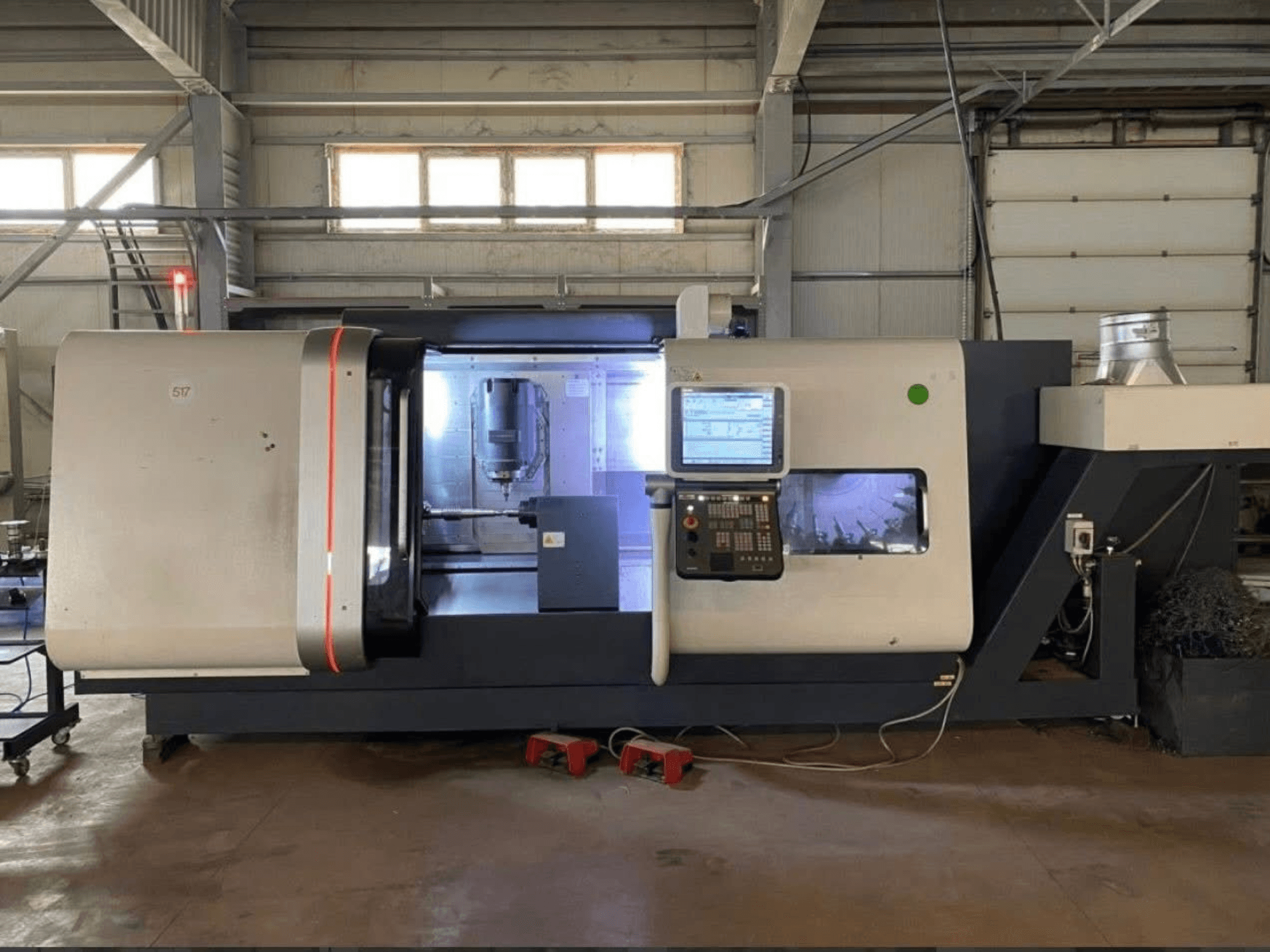 DMG MORI Beta 1250 TC frēzēšanas centrs, priekšējais skats ar vadības paneli, apgaismotu darba vietu un redzamiem griezējinstrumentiem.
