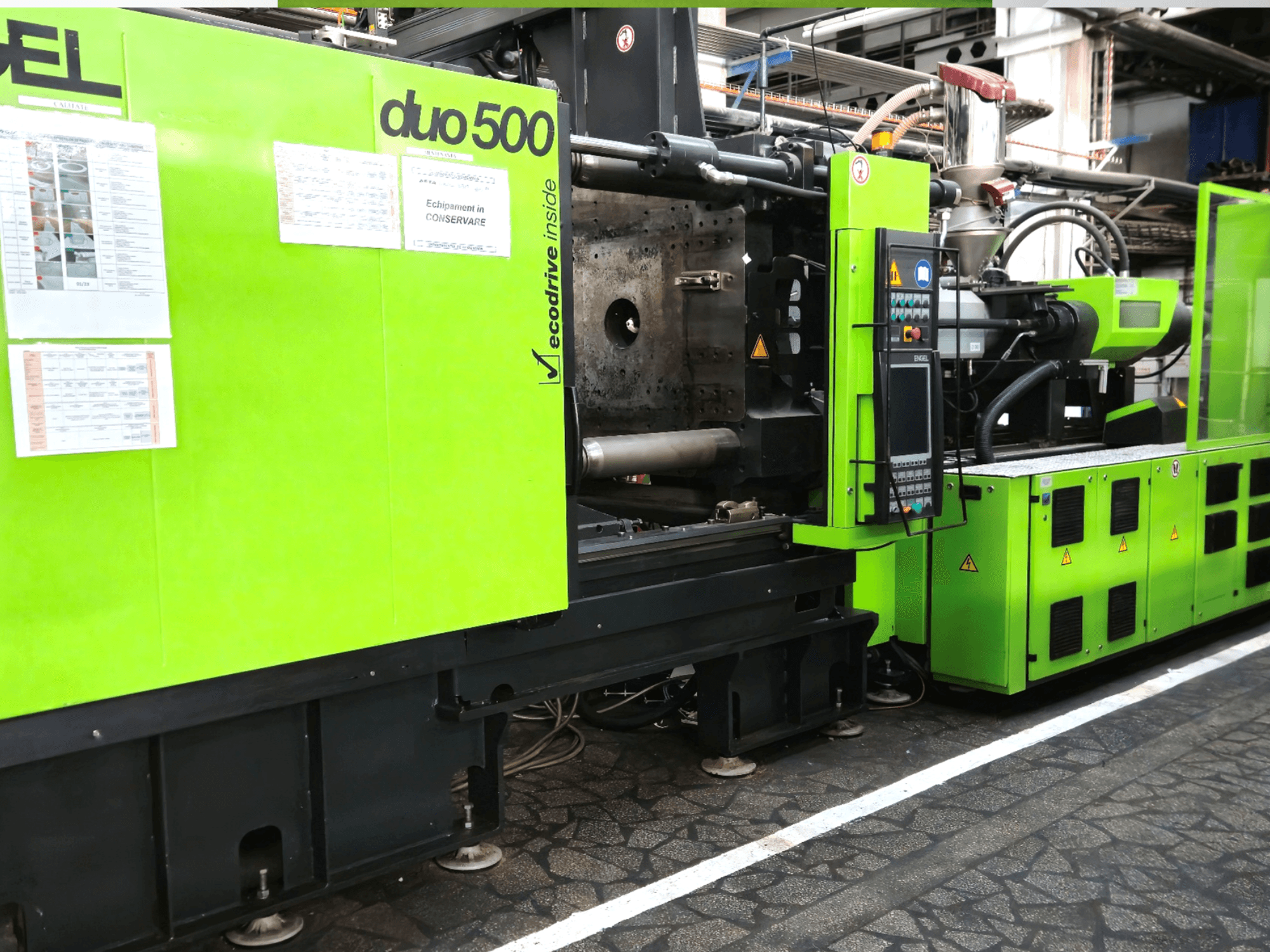 Zaļa industriālā iekārta Ergotron duo 500, skats no priekšpuses; ar vadības paneli, tehniskajām detaļām un aprīkojuma drošības uzlīmēm.