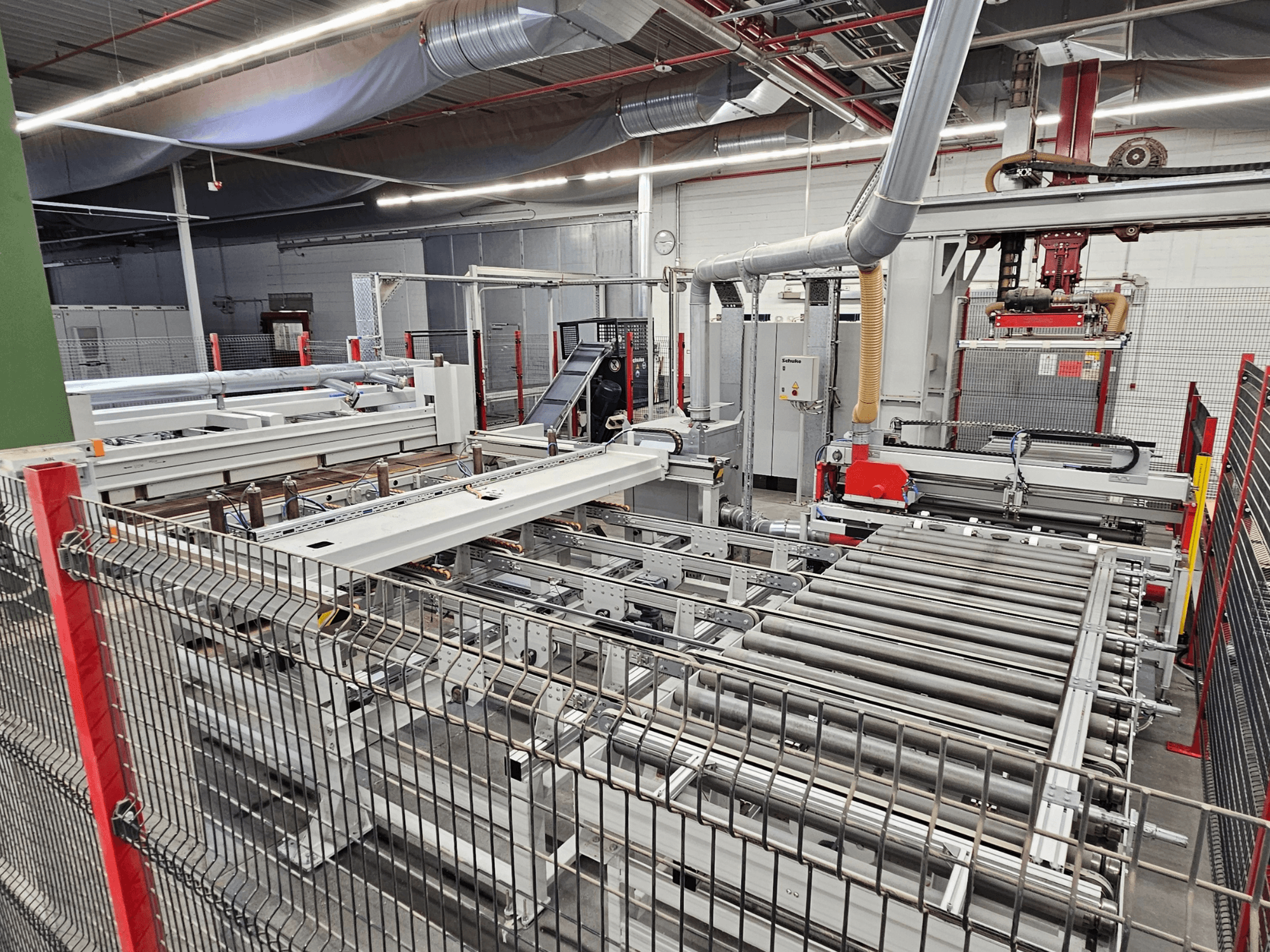 HOLZMA HPP81-3200 paneļzāģis HOLZMA HPP81-3200 parādīts priekšējā skatā, ar konveijera veltņiem un mašīnu sastāvdaļām darbnīcā.