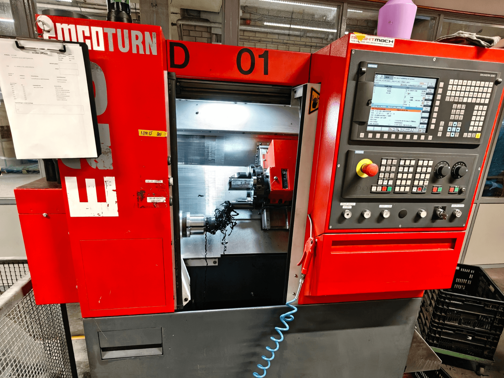 EMCO TURN E25 horizontālās virpošanas mašīnas priekšējais skats ar vadības ierīcēm, instrumentu turētāju un darba zonu ar skaidām.