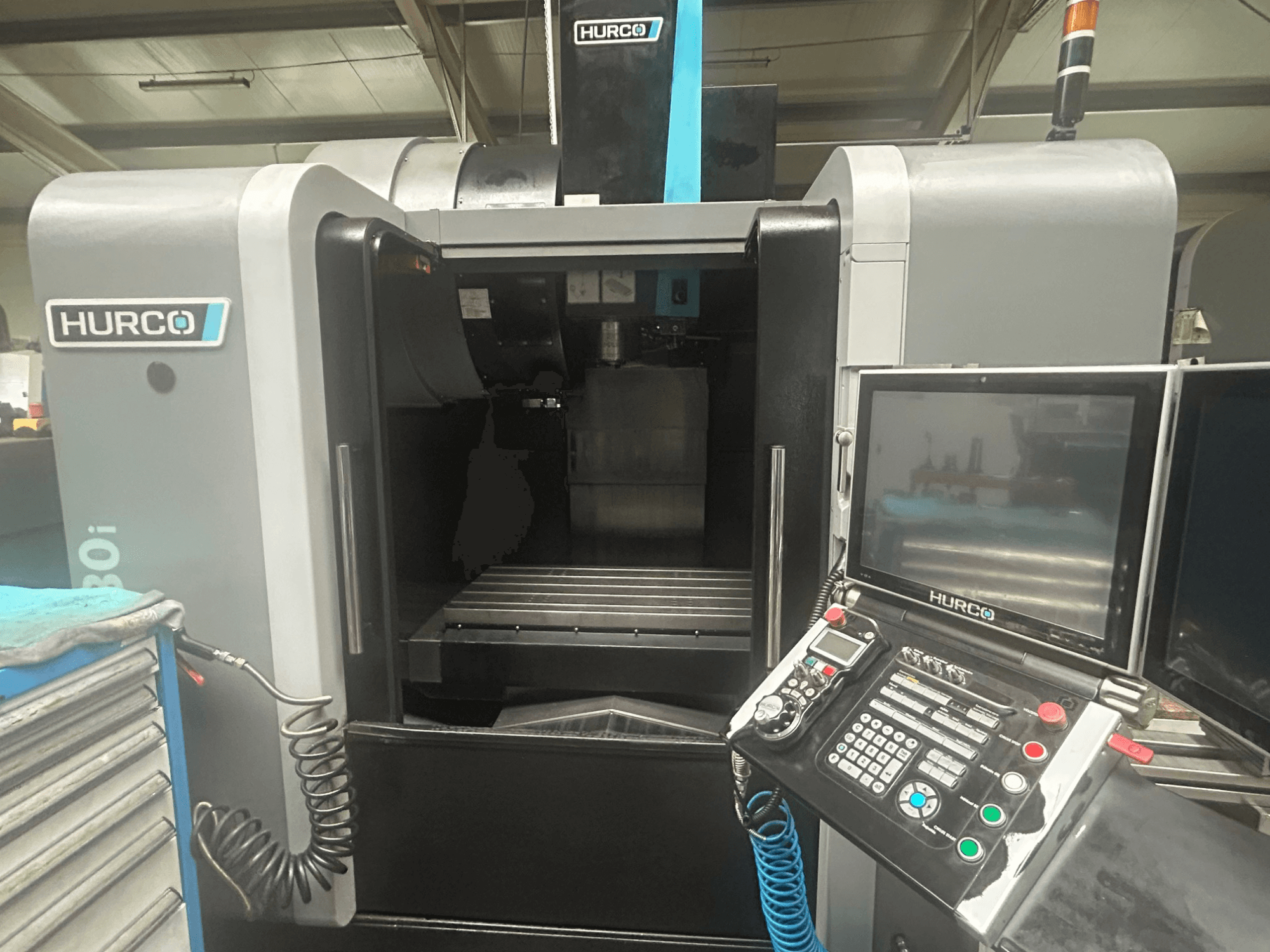 Hurco VM30i CNC mašīnas priekšējais skats ar vadības paneli ar pogām, displeju un instrumentu glabāšanas vietu.