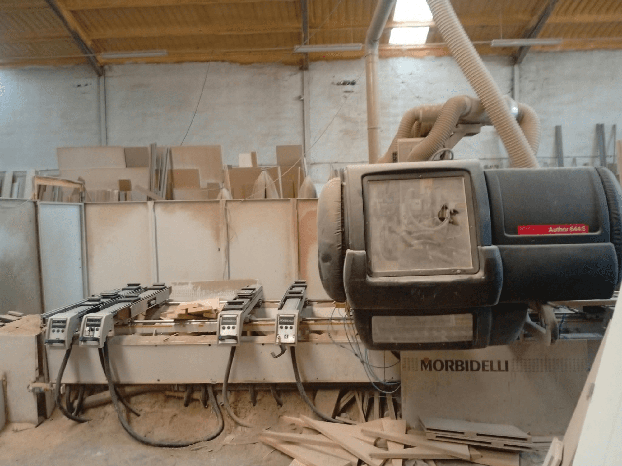 CNC apstrādes centrs MORBIDELLI A644S FTP 41 PC, kas izstādīts darbnīcā, redzams no priekšpuses ar putekļiem un koksnes atliekām.