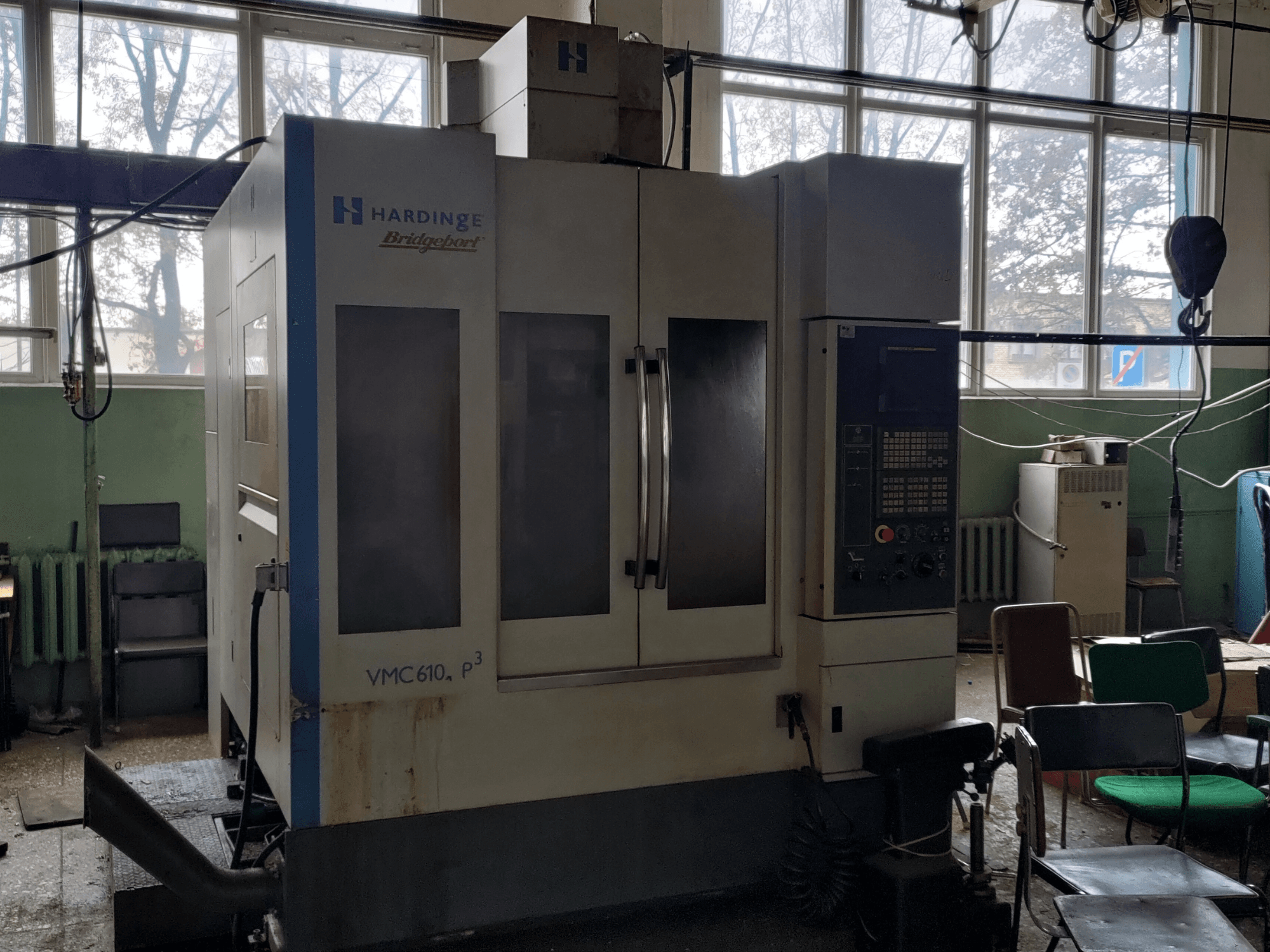 Vertikālais apstrādes centrs „Bridgeport VMC-610 XP3“ no priekšpuses, kurā redzams vadības panelis un lielās stikla durvis.
