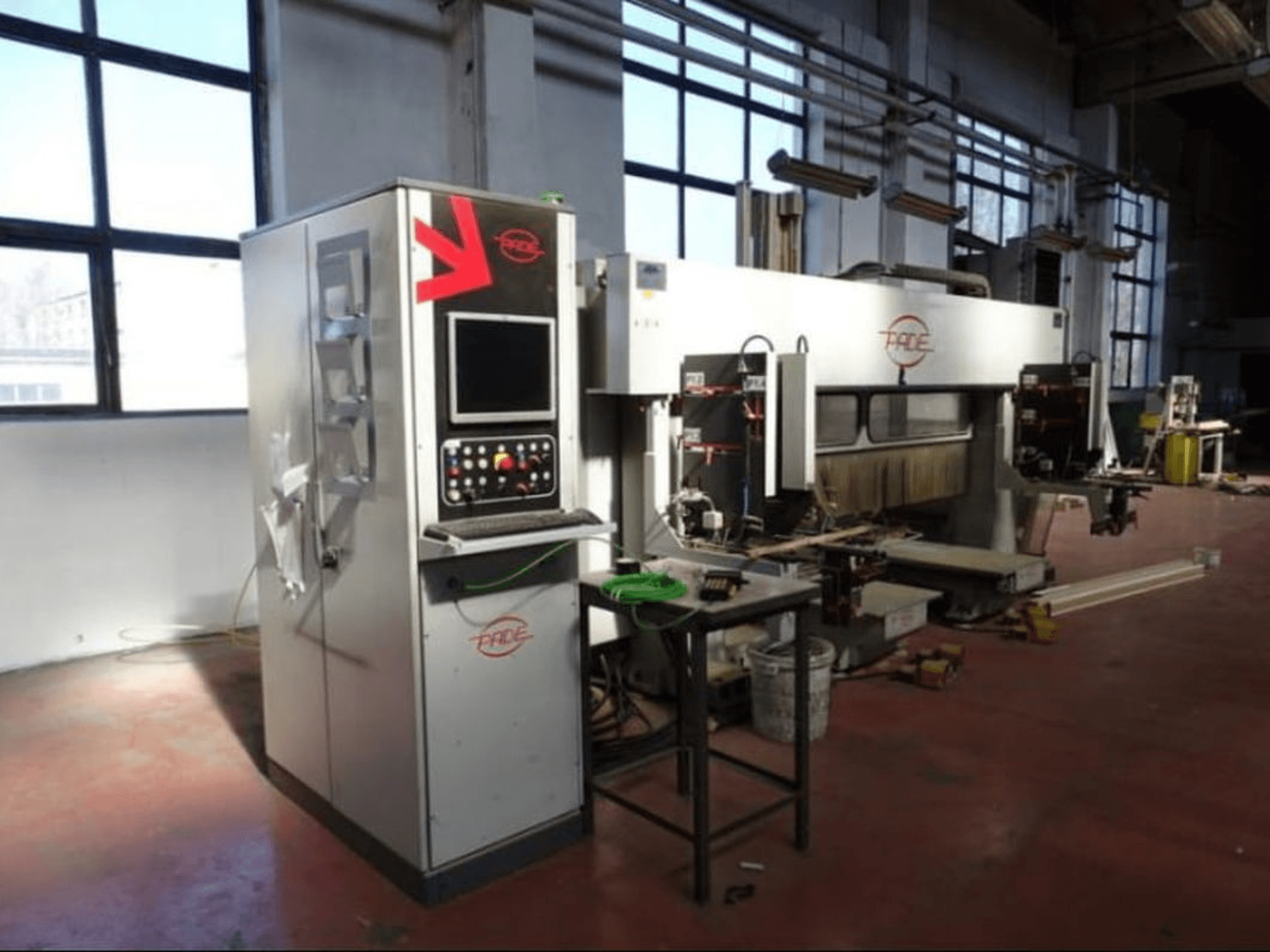 CNC koka apstrādes centrs „PADE VELUX“ — skats no priekšpuses ar vadības paneli, redzamiem instrumentiem un koka gabaliem labi apgaismotā darbnīcā.