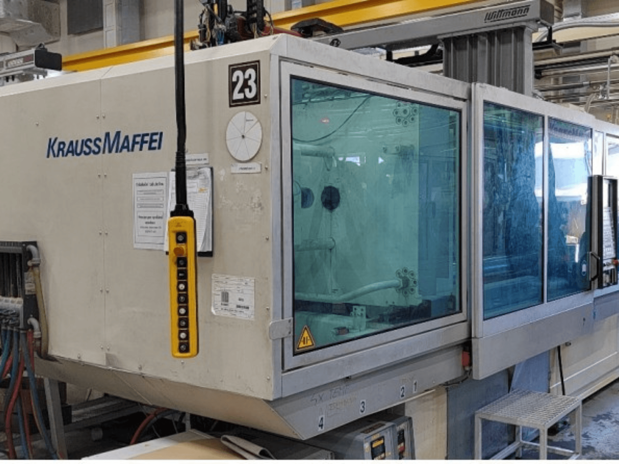Krauss Maffei KM 350-1900 C2 hidrauliskā injekcijas formēšanas mašīna, skats no priekšpuses, kurā redzams vadības panelis un caurspīdīgs drošības apvalks.