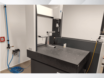 MSR mērierīce laboratorijā, priekšējais skats, kurā redzams granīta galds, kalibrēšanas sfēra un pieslēgtie palīgrīki.