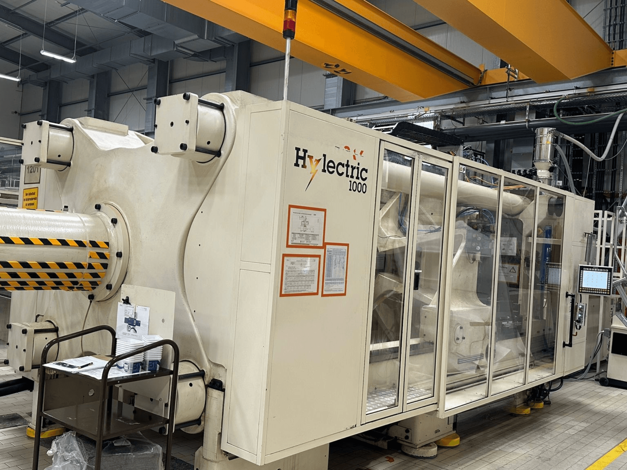 Elektriskā plastmasas liešanas mašīna „Husky Hylelectric H1000 RS95/80“, skats no sāniem, kurā redzams vadības panelis un drošības ierīces.