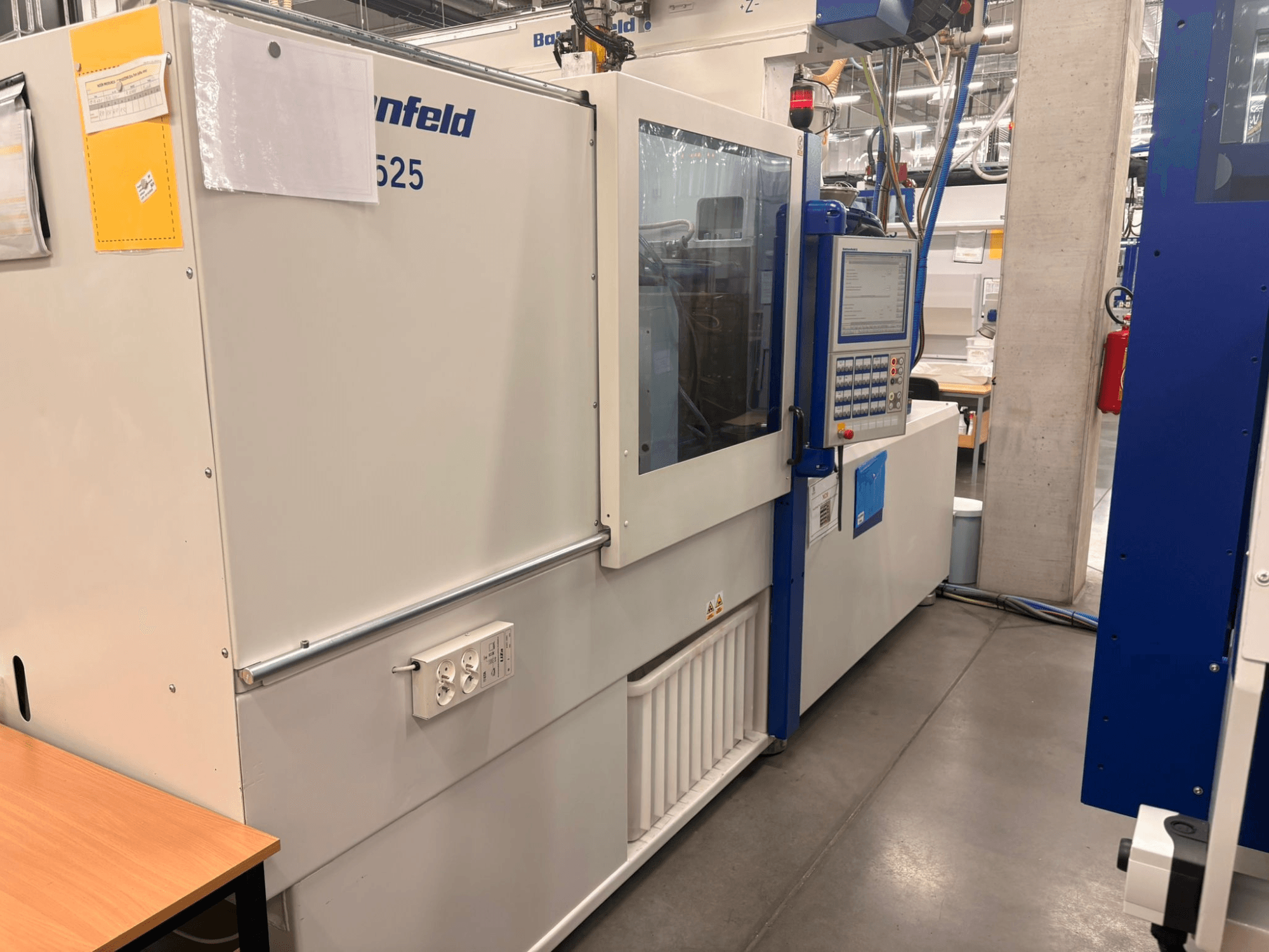 Mašīnas Arburg, modelis 620S, priekšējais skats, kurā redzams vadības panelis un strāvas pieslēgvietas rūpnīcas apstākļos.