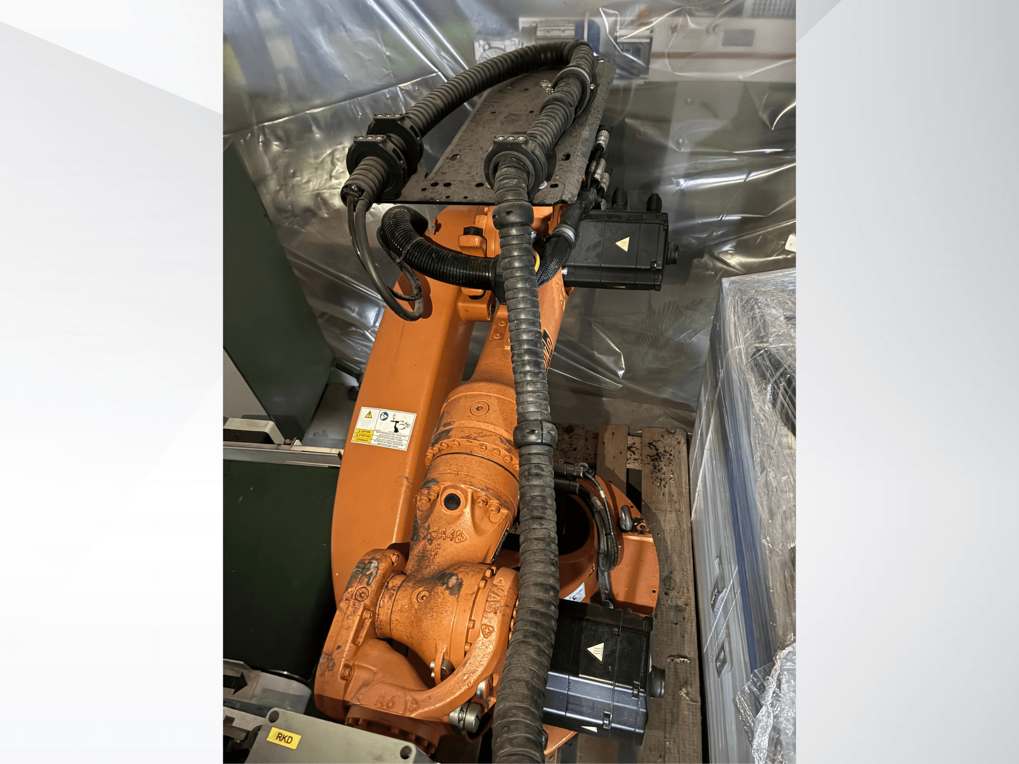KUKA KR16-2 robota roka oranžā krāsā, skats no augšas, kurā redzami savienotāji un aizsargcaurules.