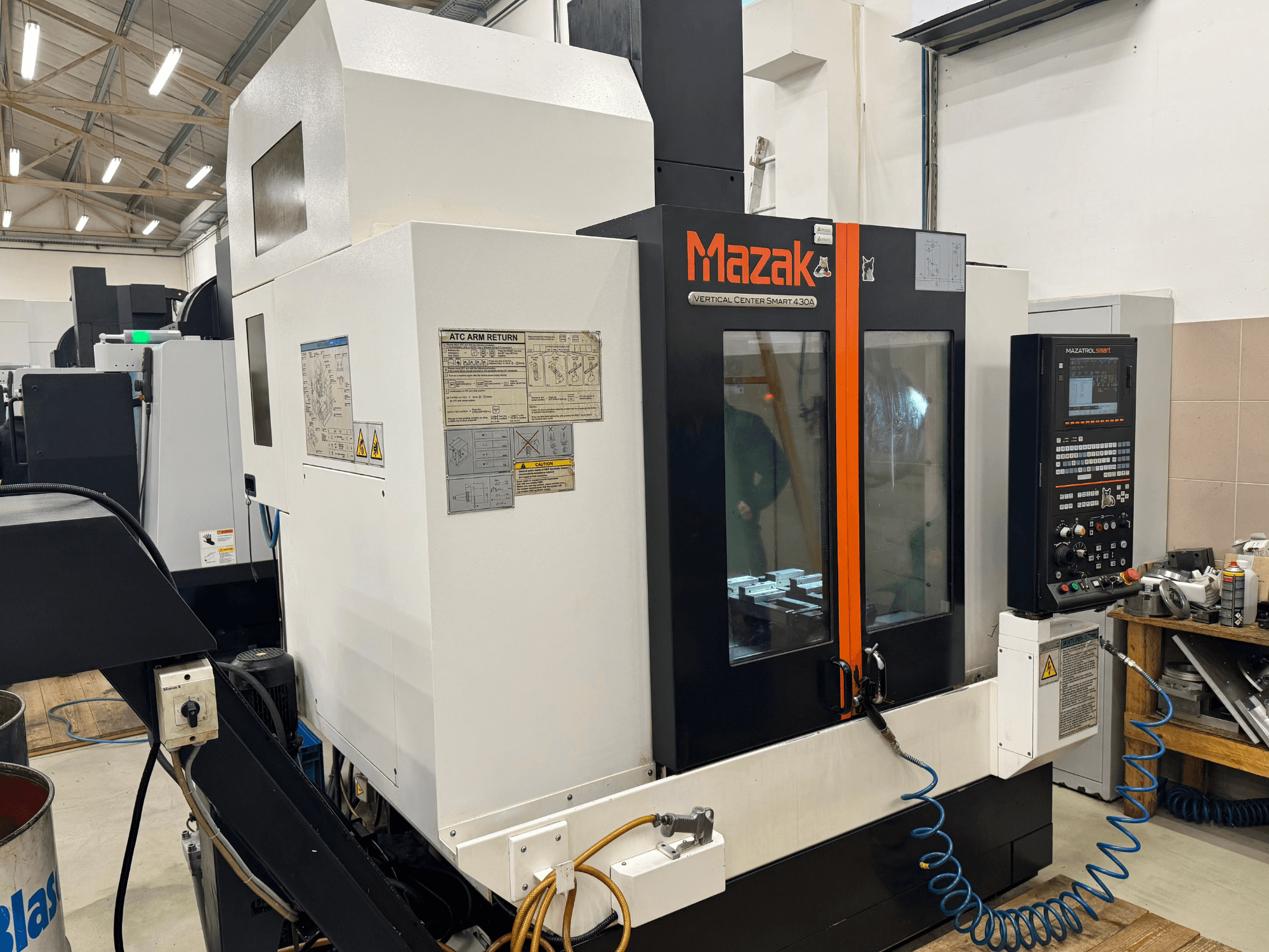 Mazak Vertikālais centrs Smart 430A, skats no priekšpuses; CNC frēzmašīna ar vadības paneli, caurspīdīgu korpusu un redzamu instrumentu turētāju.