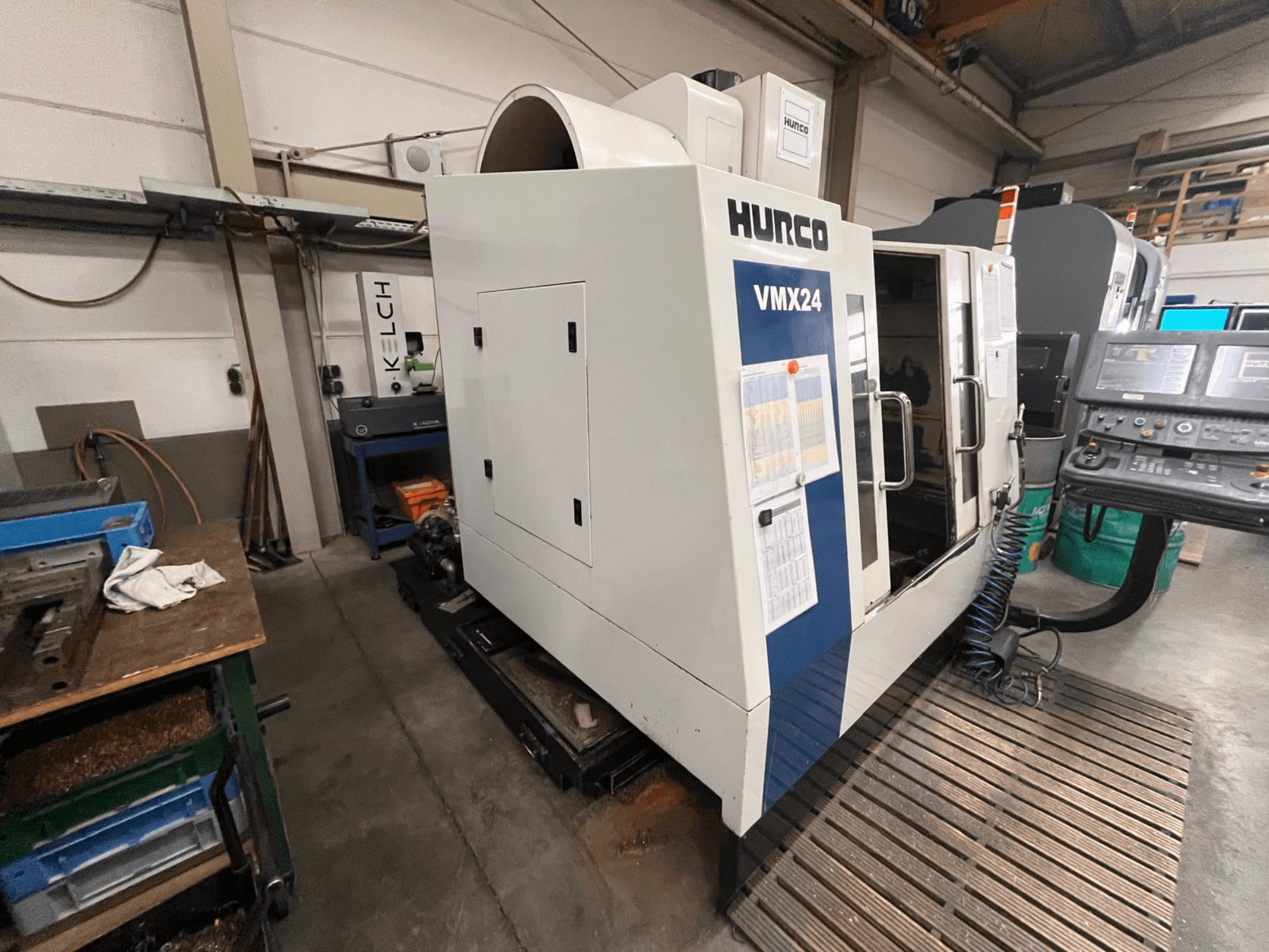 Hurco VMX24 CNC darbnīcā, skats no priekšpuses; vadības panelis un atvērtas piekļuves durvis.