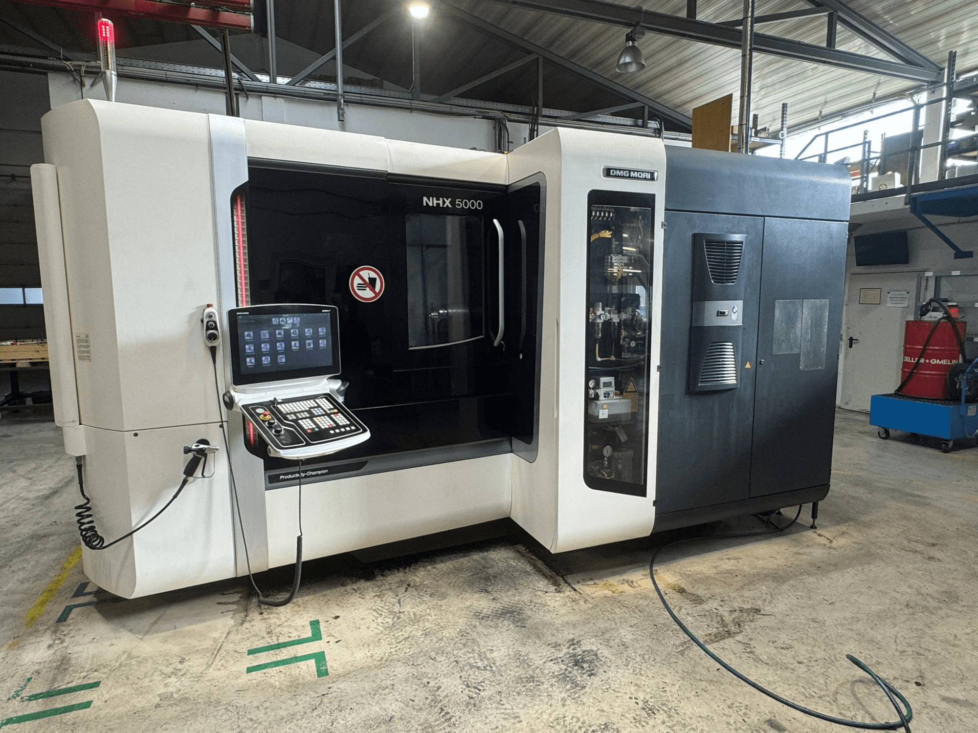 DMG MORI NHX 5000 horizontālais apstrādes centrs, skats no priekšpuses ar redzamu vadības paneli un drošības indikatoriem.
