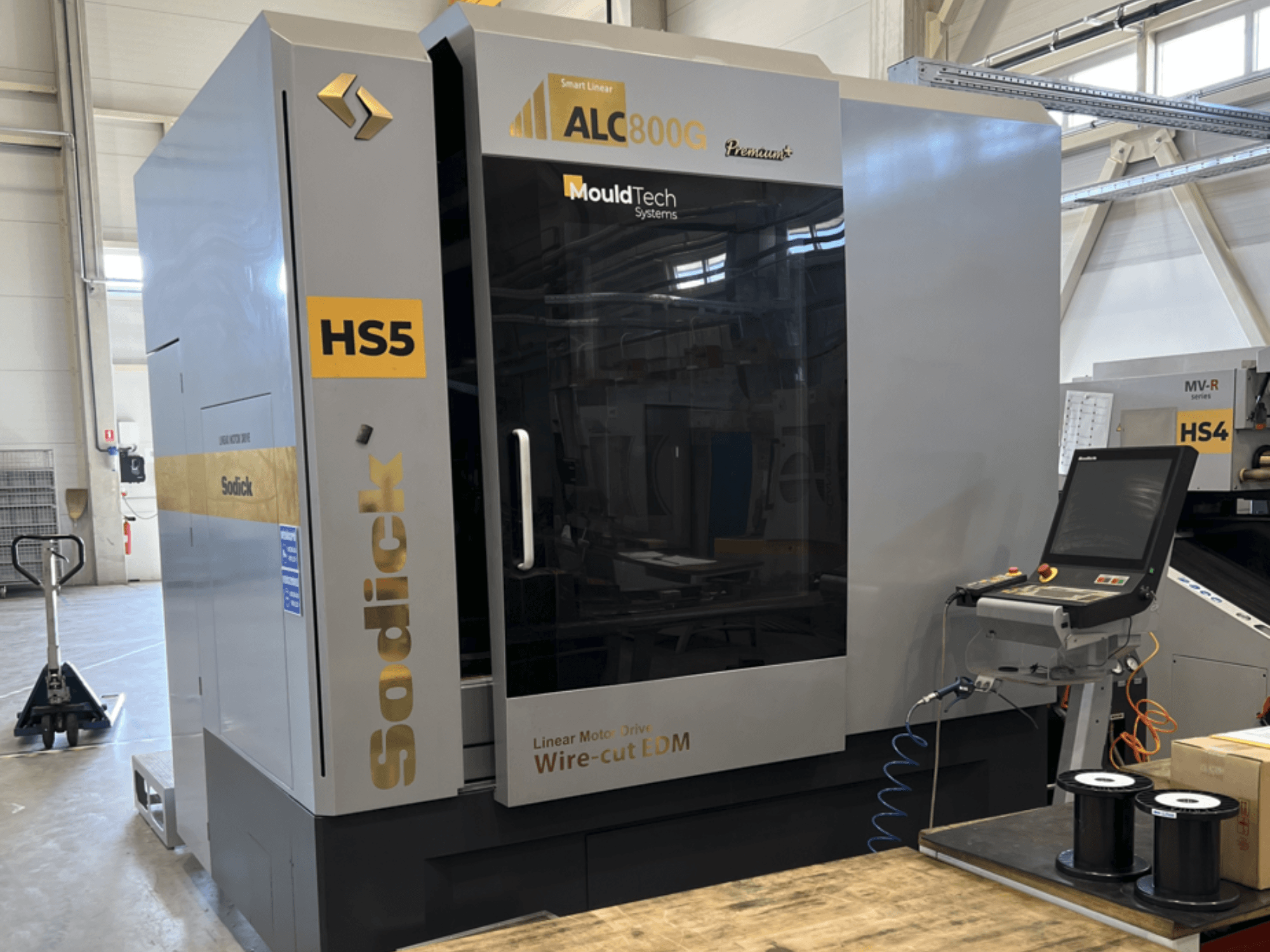 Sodick ALC800G Premium Wire EDM Machine, priekšējais skats, kurā redzams vadības panelis un sarežģītas dizaina detaļas.