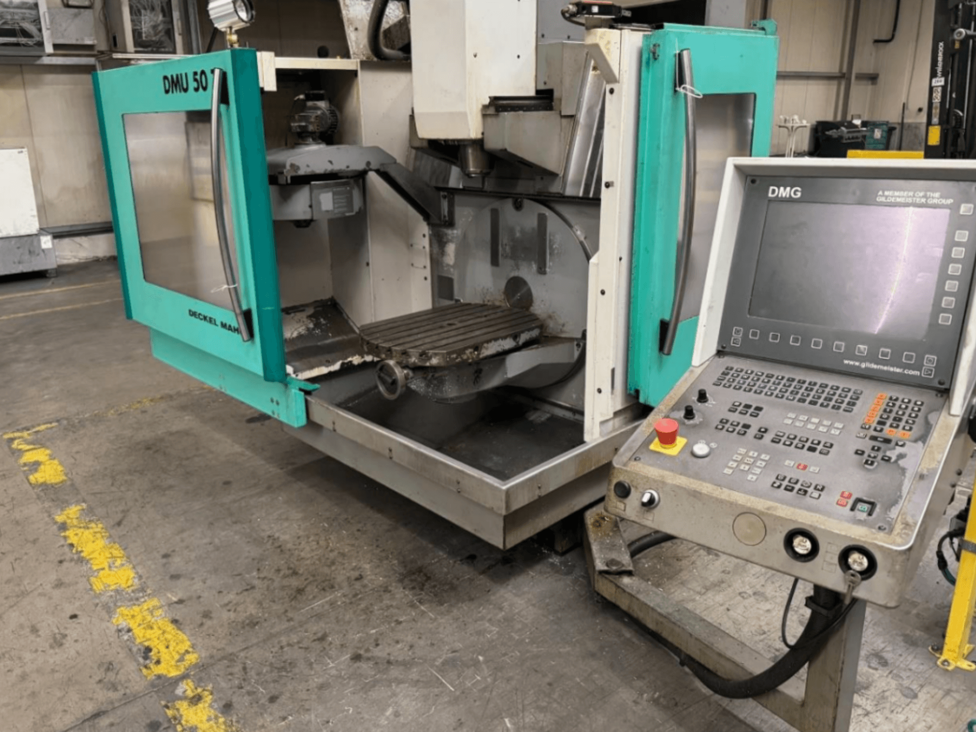 DMG DMU 50 frēzmašīna ar atvērtām durvīm, kas parāda iekšpusi un vadības paneli, skatoties no priekšpuses.