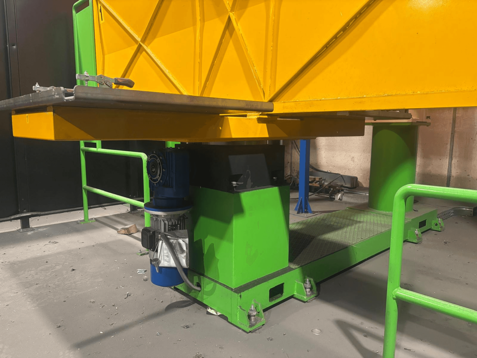 Zaļas un dzeltenas krāsas rūpniecības iekārtas no zema priekšējā skata, ar motoru un platformu ar teksturētu virsmu.