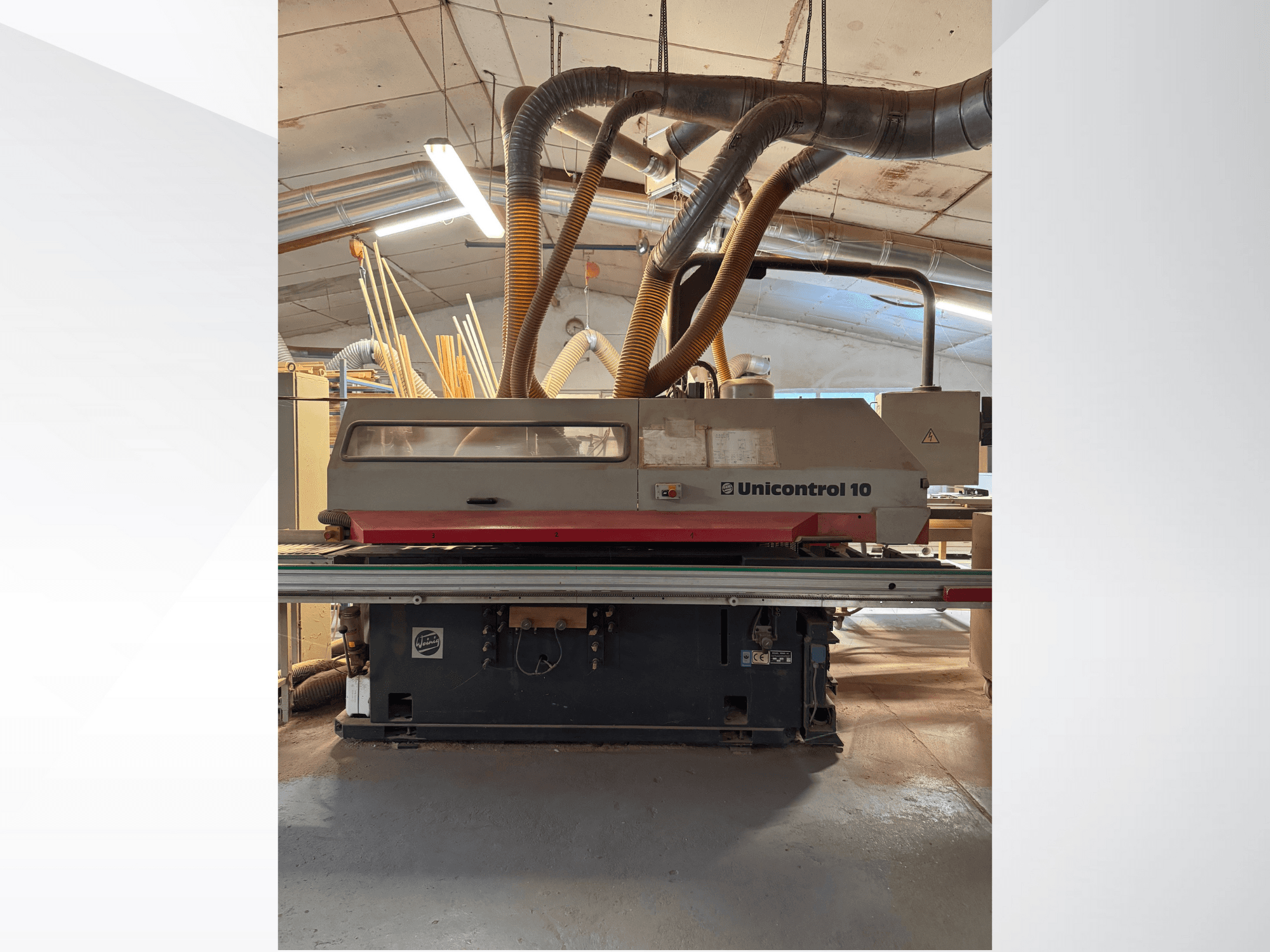 Kokapstrādes mašīnas Unicontrol 10 priekšējais skats ar putekļu nosūces caurulēm un darbības vadības ierīcēm.