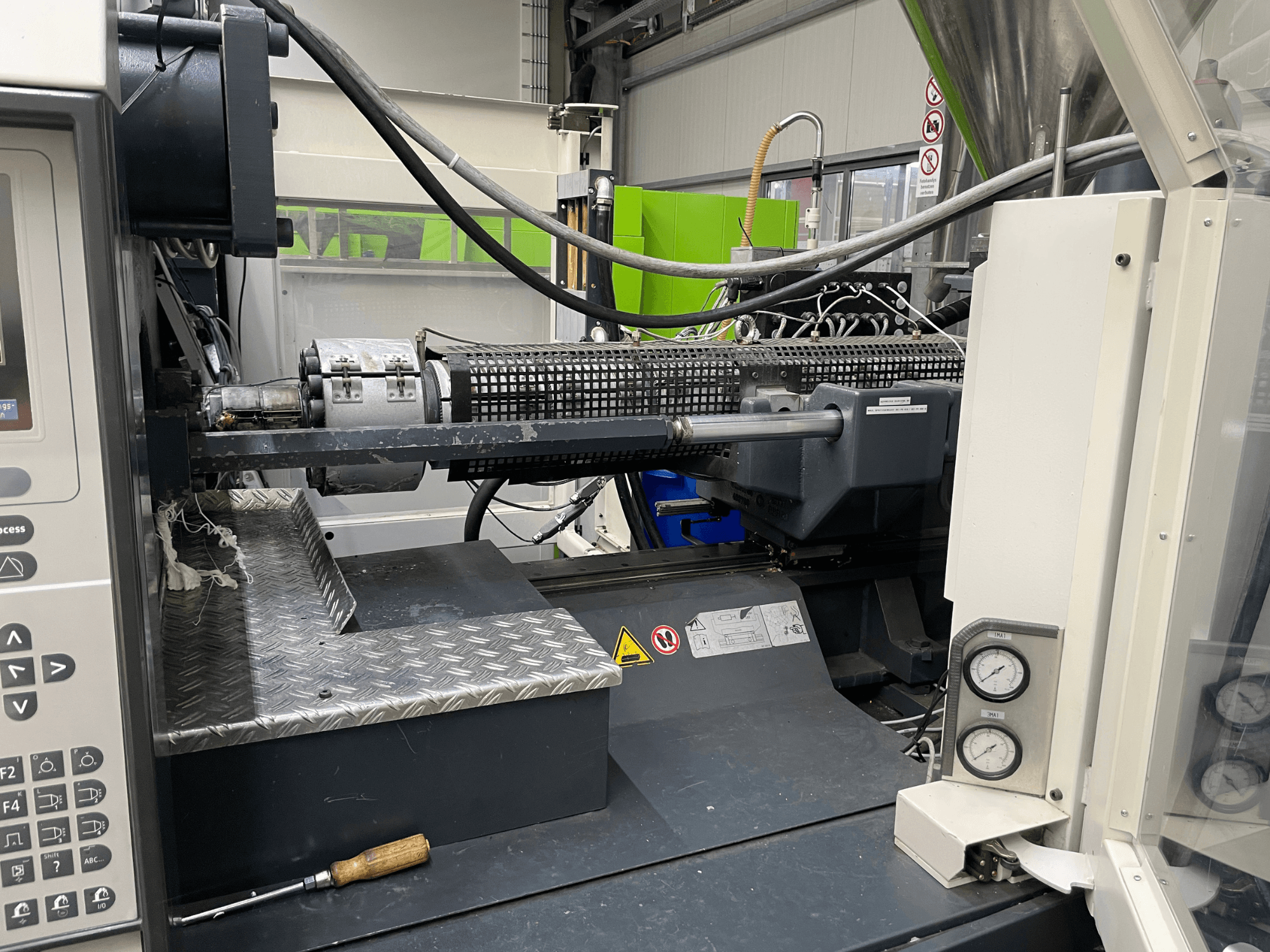 Iesmidzināšanas iekārtas sānu skats ar redzamu vadības paneli, ekstrūderi un spiediena mērinstrumentiem, kas ir ideāli piemērots ražošanas uzdevumiem.