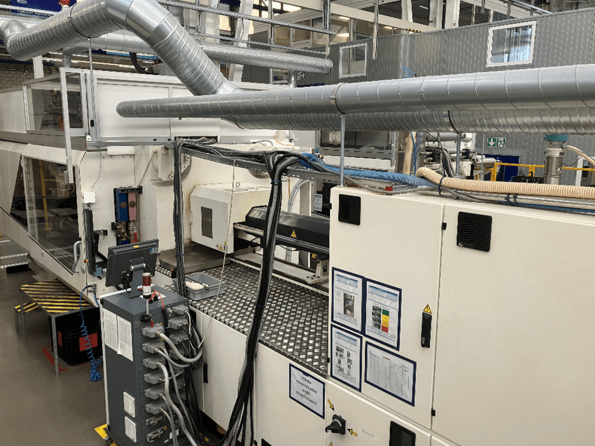 Rūpnieciskās iekārtas ar plašu cauruļvadu sistēmu, vadības paneli un ekspluatācijas rokasgrāmatām, skatoties no augšas uz leju.