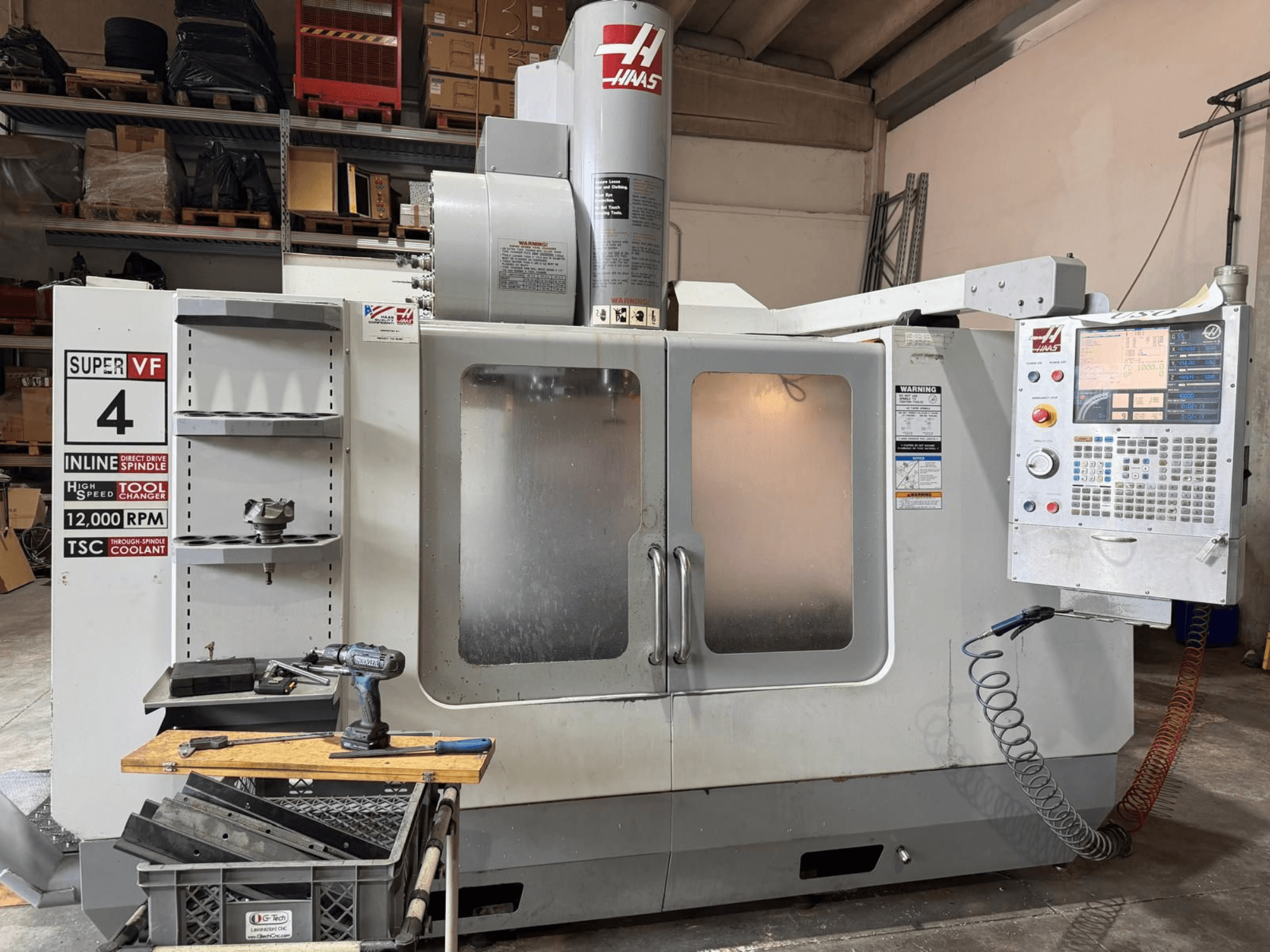 HAAS VF-4SSHE vertikālā apstrādes centra skats no priekšpuses ar vadības pulti, instrumentu turētāju un vārpstu ar 12 000 apgr./min.; ātrdarbīga, precīza mašīna.