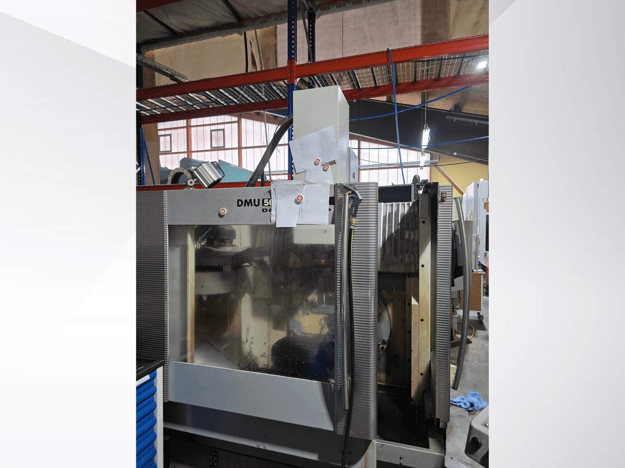 DMU 50 3 asu CNC apstrādes centrs darbnīcā, parādīts no priekšpuses, ar darbības komponentiem un pievienotajiem dokumentiem.