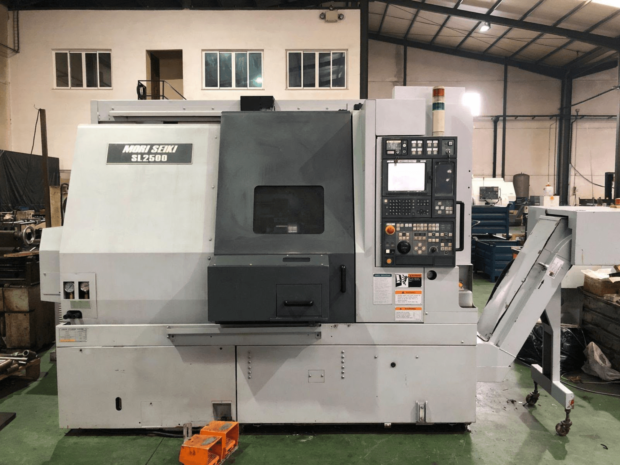 DMG Mori Seiki SL 2500 Y pagrieziena-frēzēšanas centrs, sānskats, kurā redzams vadības panelis un skaidu konveijers.