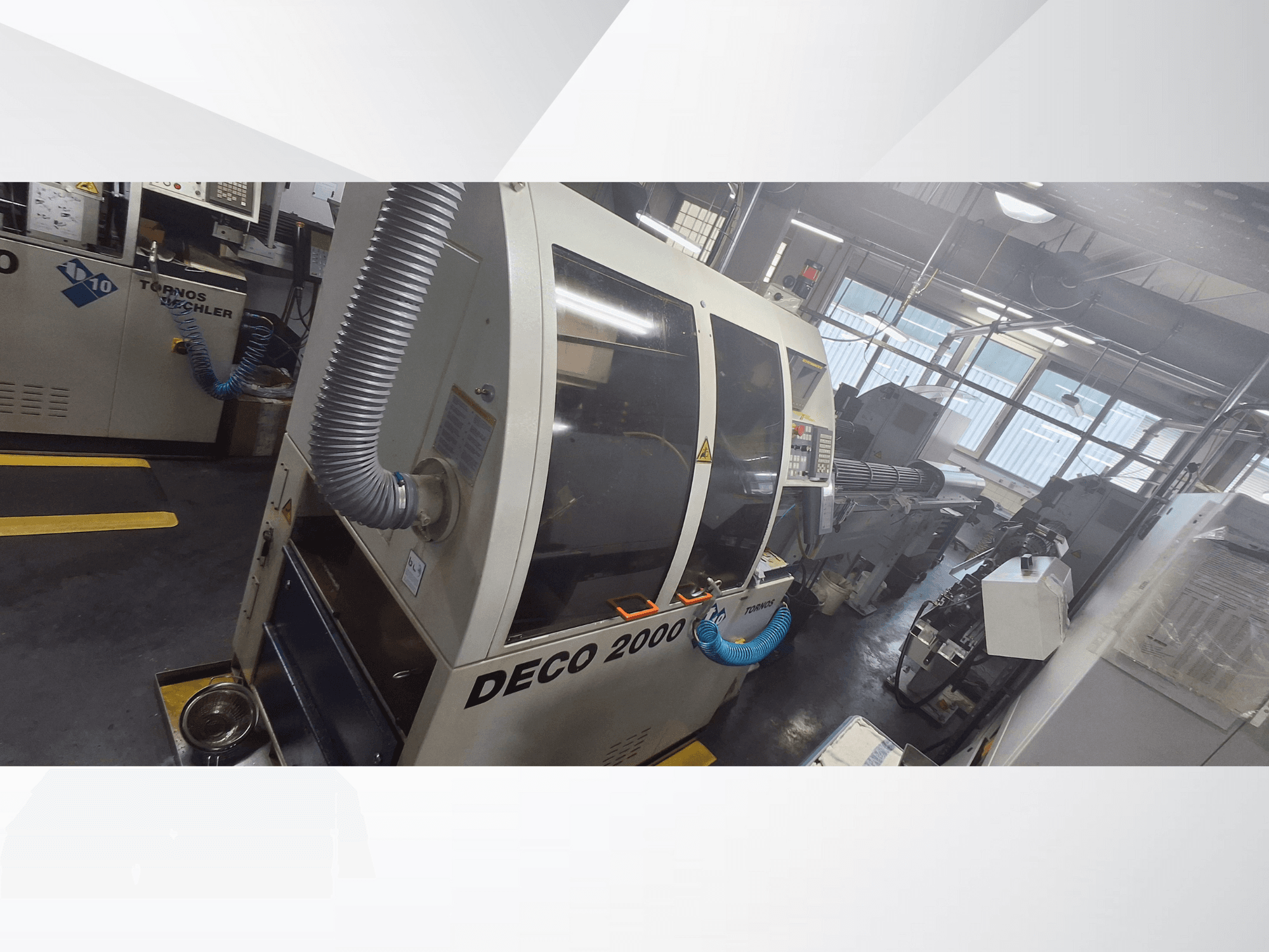 DECO 2000 CNC darbnīcā, skats no priekšpuses, ar ventilācijas šļūteni un vadības paneli, paredzēts precīzai apstrādei.