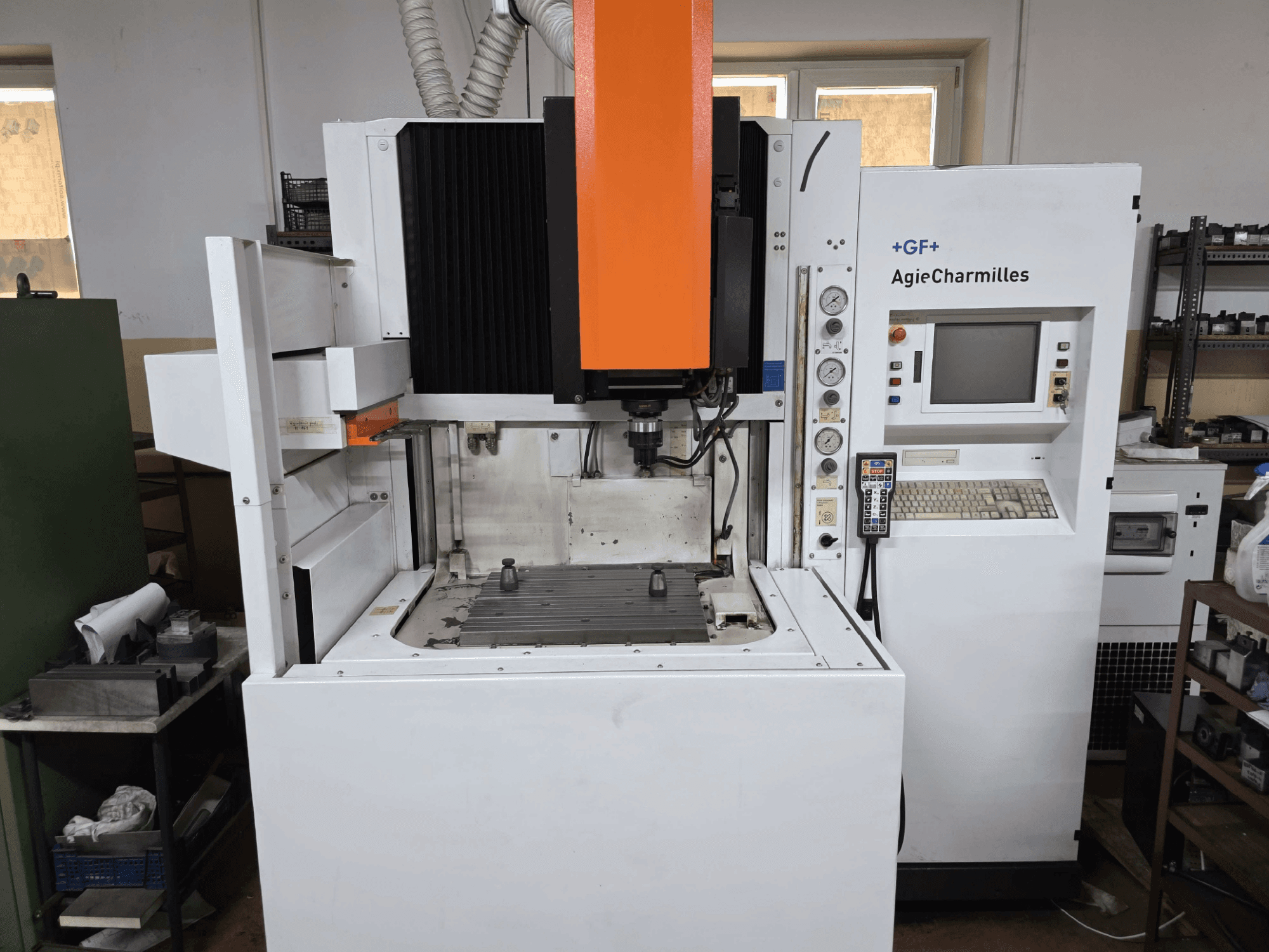 GF AgieCharmilles CNC darbgalds, skats no priekšpuses ar izteikti oranžu vārpstu, digitālo vadības paneli un uzstādīto urbšanas galdu.