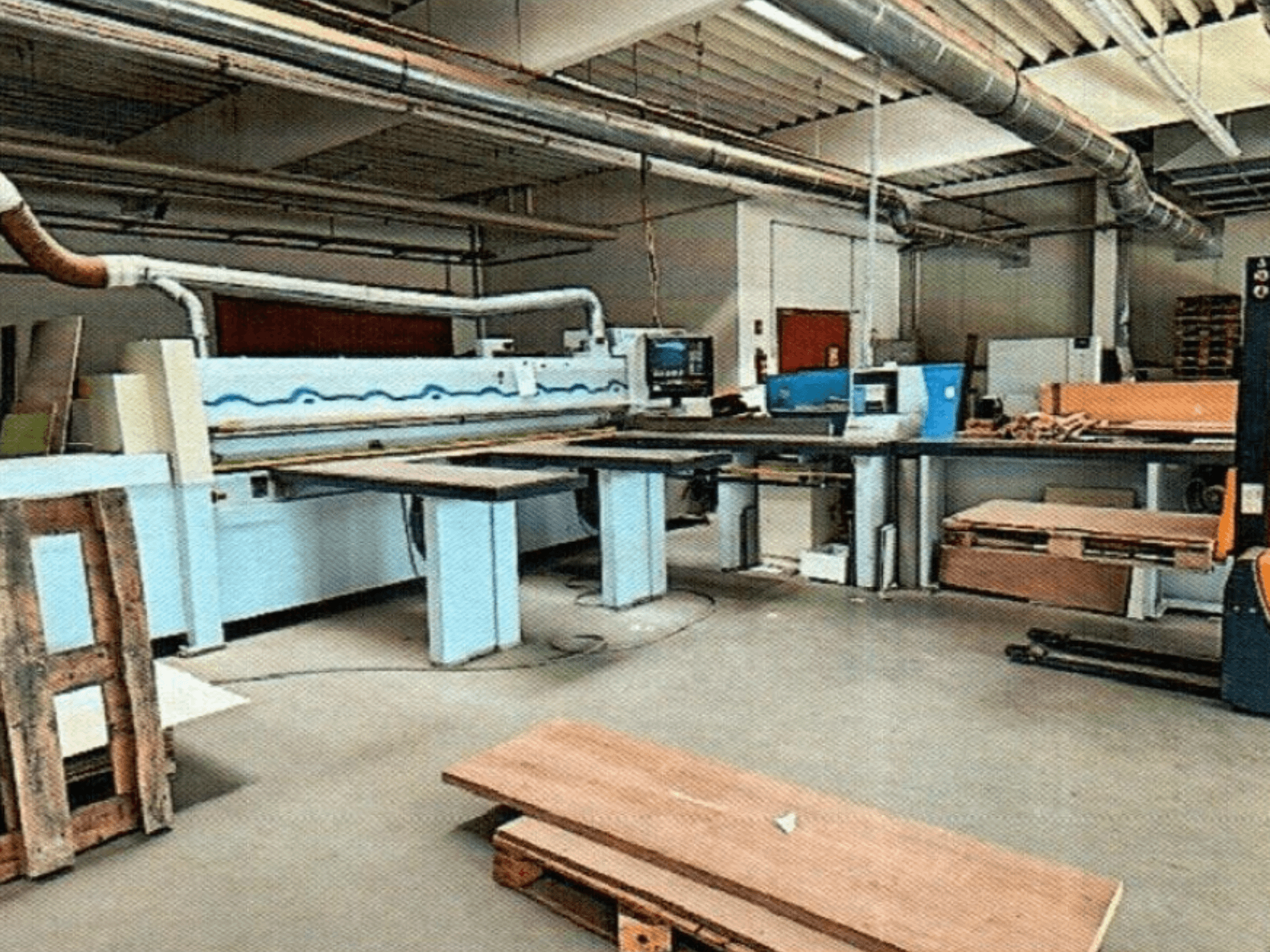 HOMAG HPL 11/38/22 paneļu zāģis darbnīcā ar lielu griešanas galdu un displeja konsoli, skatīts no priekšpuses.