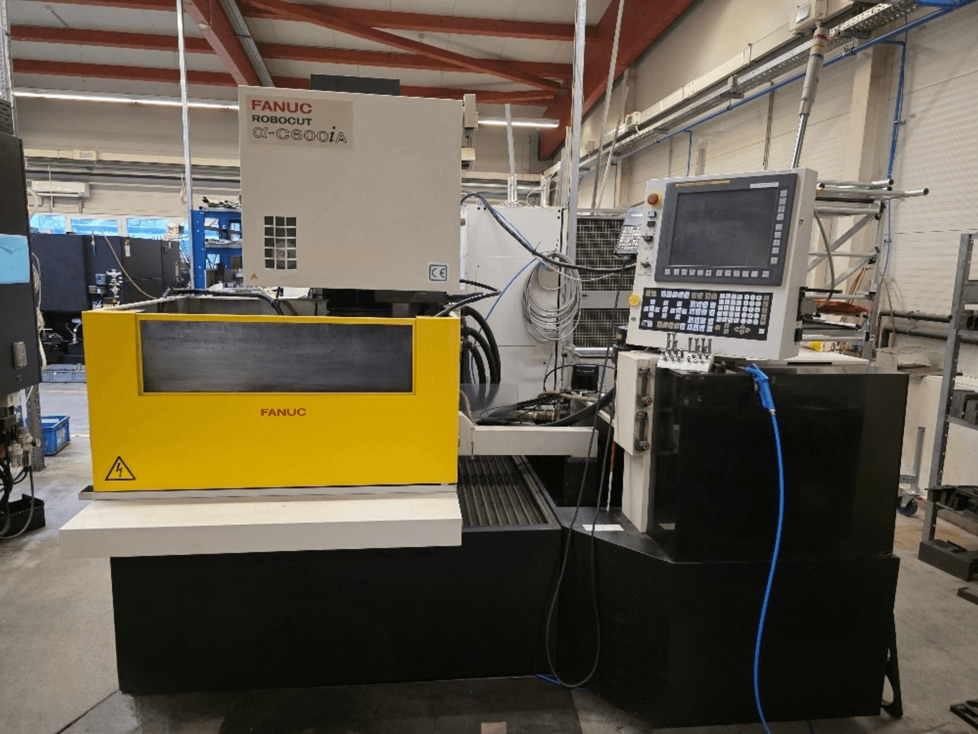 FANUC Robocut α-C600iA stiepļu griešanas mašīnas, priekšējais skats, ar dzeltenu vadības paneli un digitālo displeju.