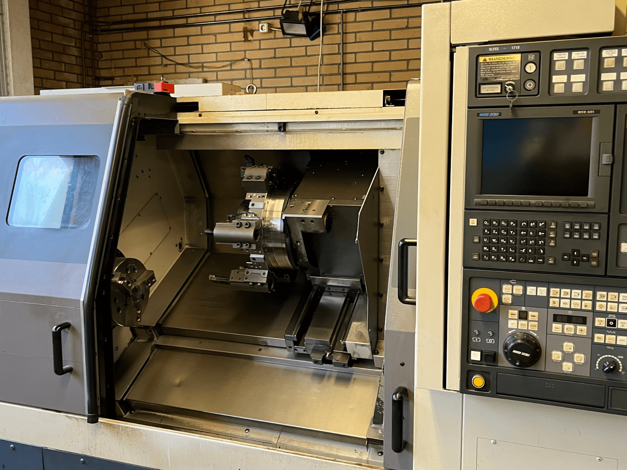 MORI SEIKI SL-253B MC/1000 horizontālās virpošanas iekārta, priekšējais skats, kurā redzams vadības panelis un atvērta kamera ar apstrādātām detaļām.