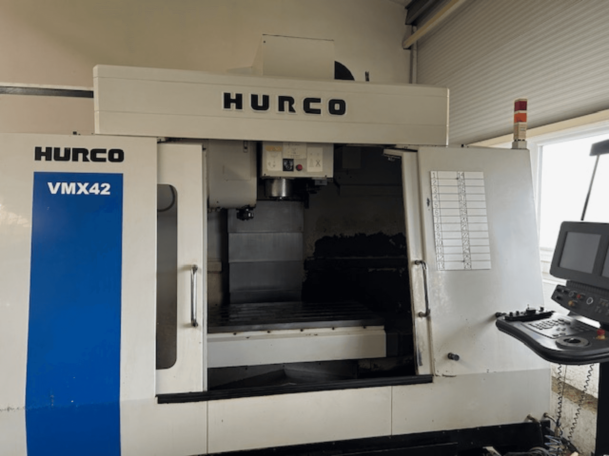 Hurco VMX42 CNC darbgalds priekšpusē, kurā redzams vadības panelis, vārpsta un darba zona; redzams darbības izkārtojums.