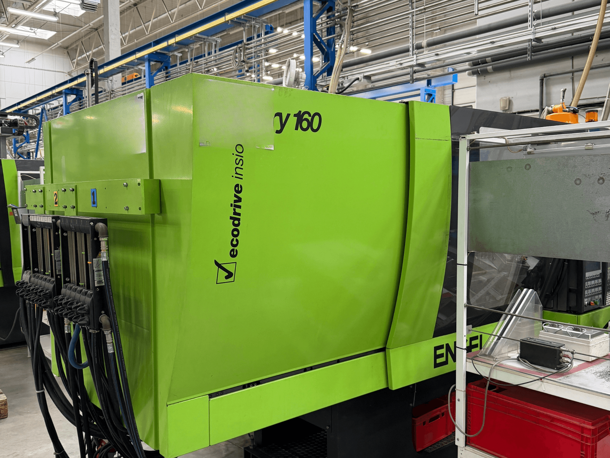 Zaļā krāsā izpildītā hidrauliskā injekcijas formēšanas mašīna „Engel Victory 500/160 tech“ — sānskats, kurā redzams vadības panelis un „Ecodrive“ funkcija.