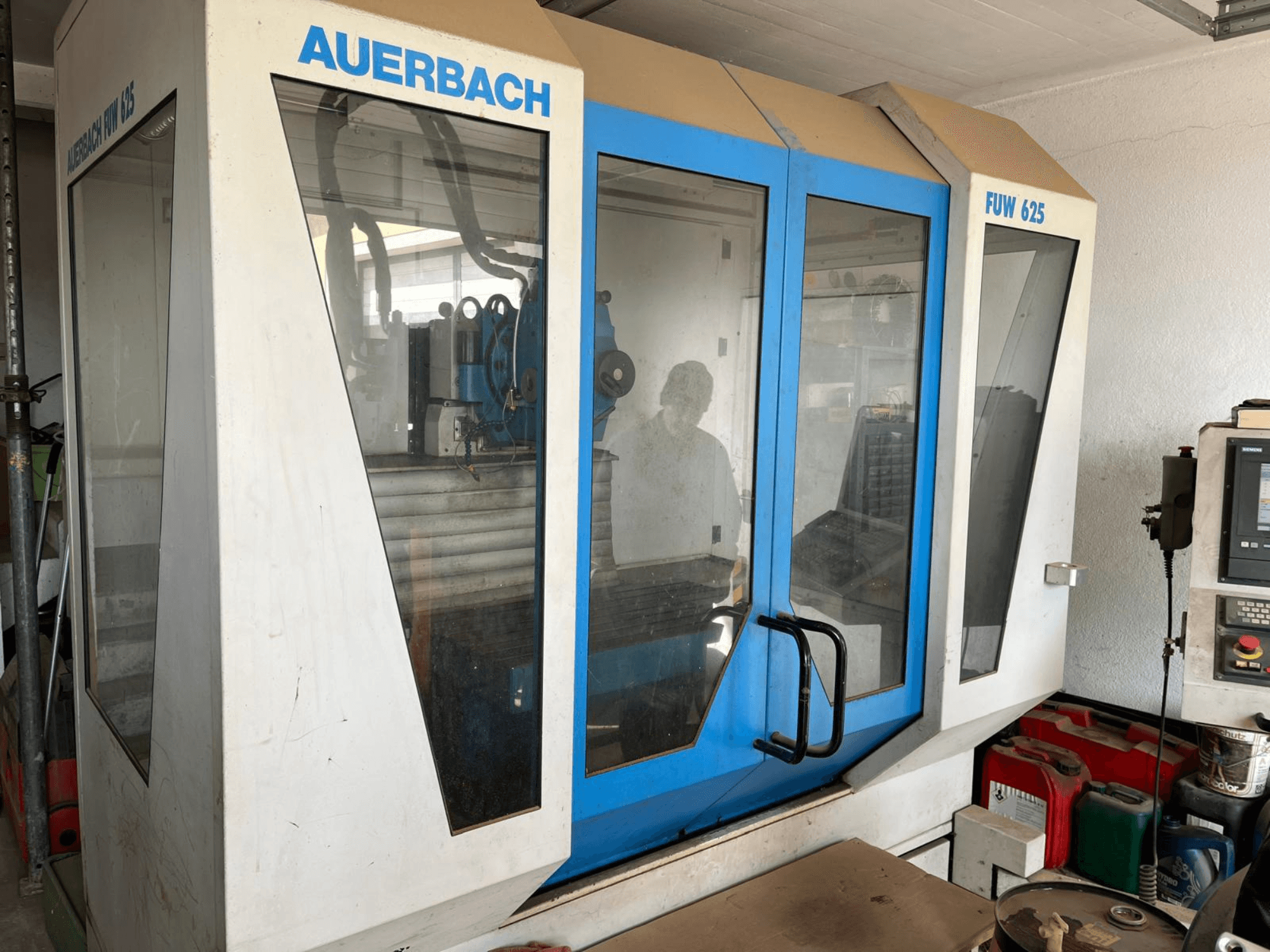 Auerbach FUW 625 universālais apstrādes centrs sānu skatā, ar stikla paneļiem un vadības paneli labajā pusē.